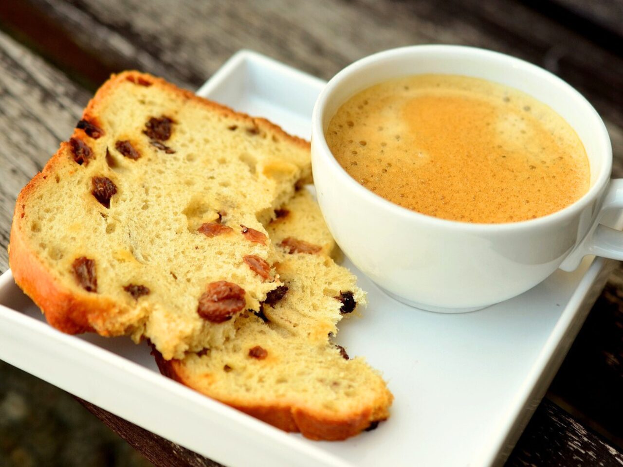 A cup of morning coffee with a piece of raisin bread
