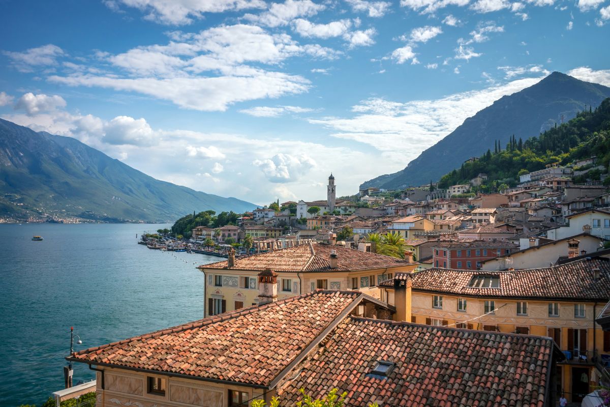 Picturesque view of Limone sul Garda, Italy, with terracotta rooftops, a charming lakeside promenade, and towering mountains surrounding Lake Garda.