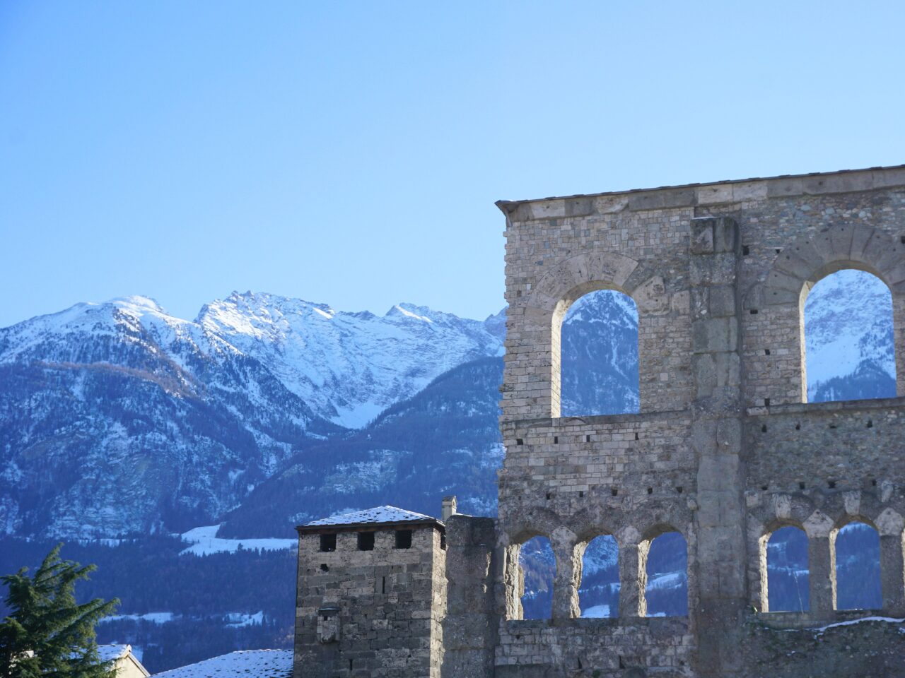 Ancient Roman theater ruins with a foggy snow mountain backdrop