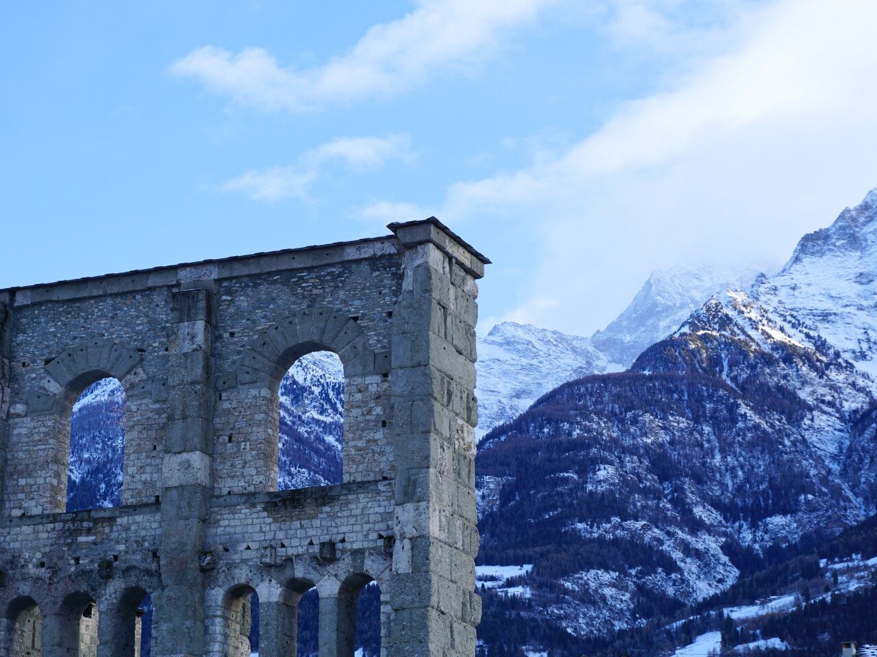 Ancient Roman theater ruins with a foggy snow mountain backdrop