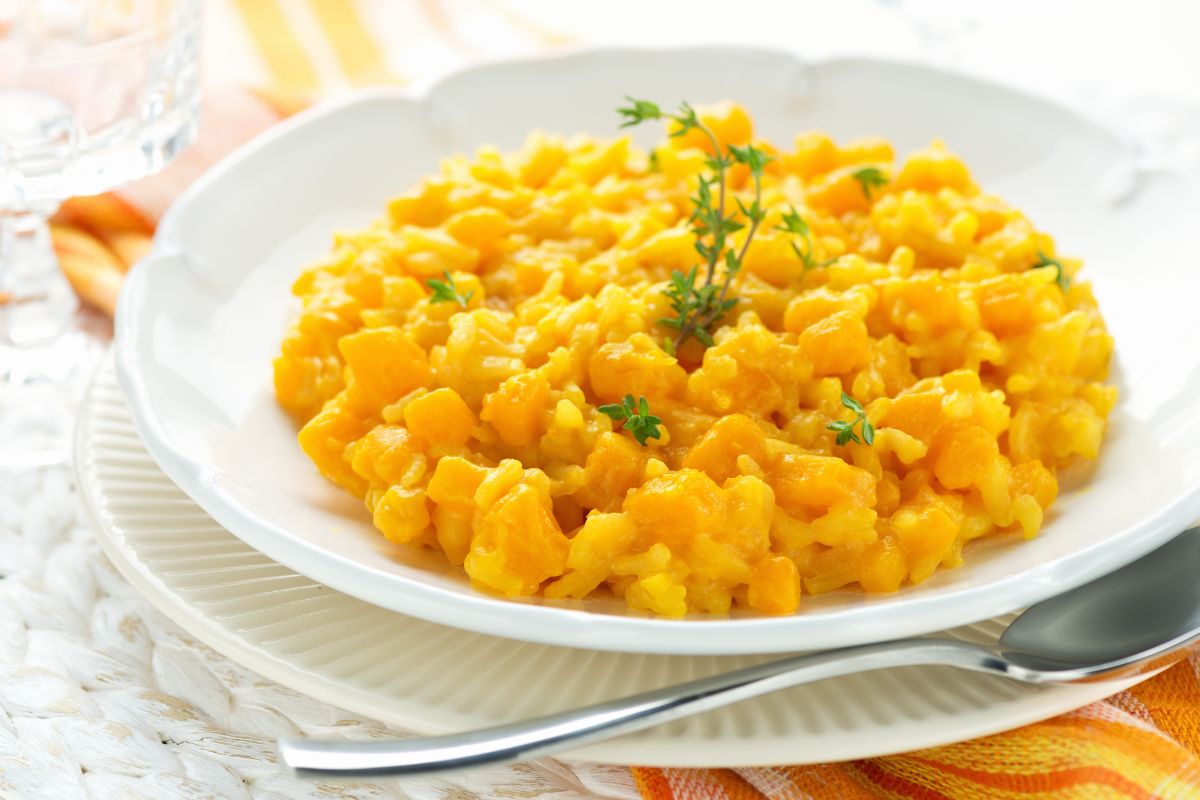 A plate of pumpkin risotto garnished with fresh herbs