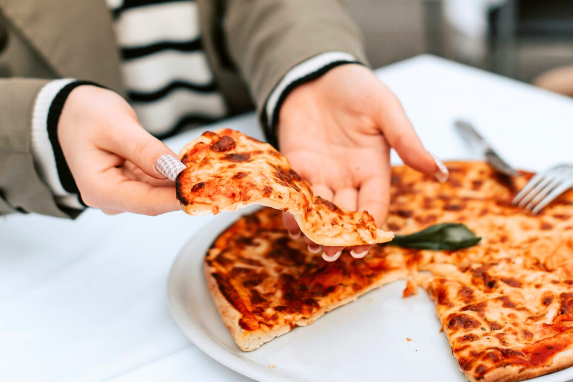 A hand lifting a slice of Italian pizza