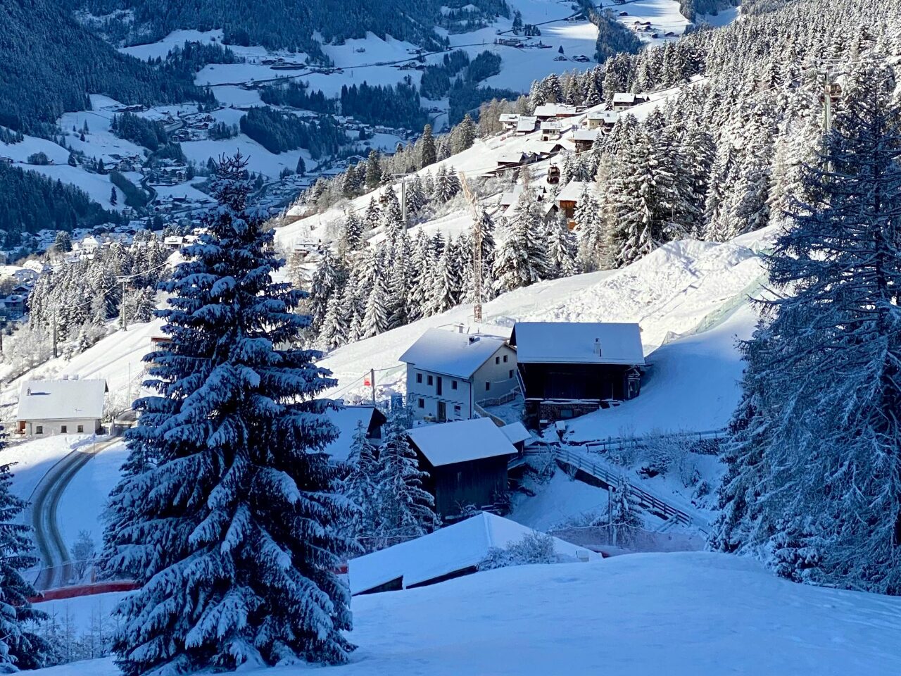 Uphill with snow-covered trees and trail. Ortisei South Tyrol, Italy. Winter landscape. Houses covered with snow.