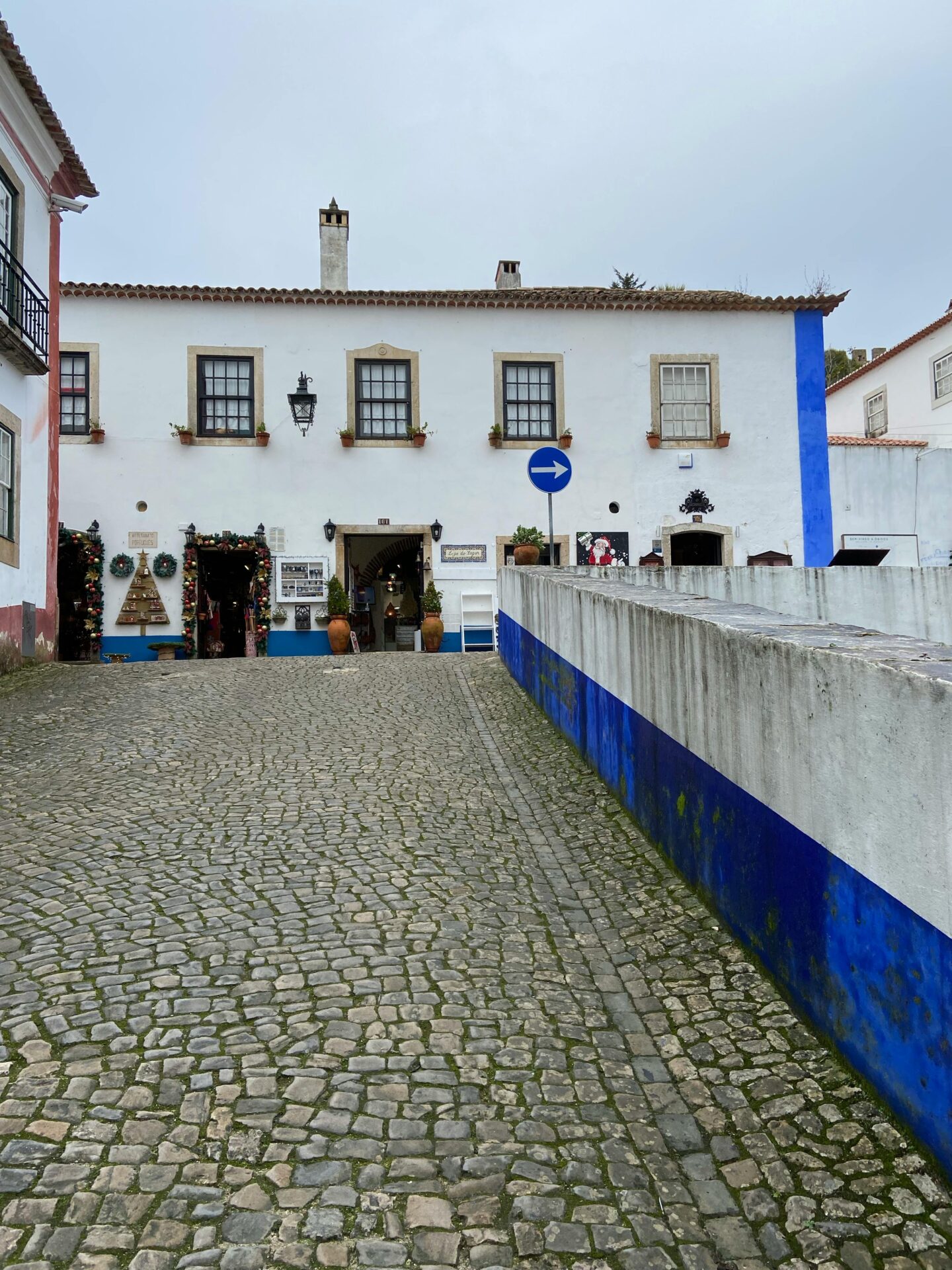 A White Concrete Building with Cobbled Pavement in Obidos, Portugal.