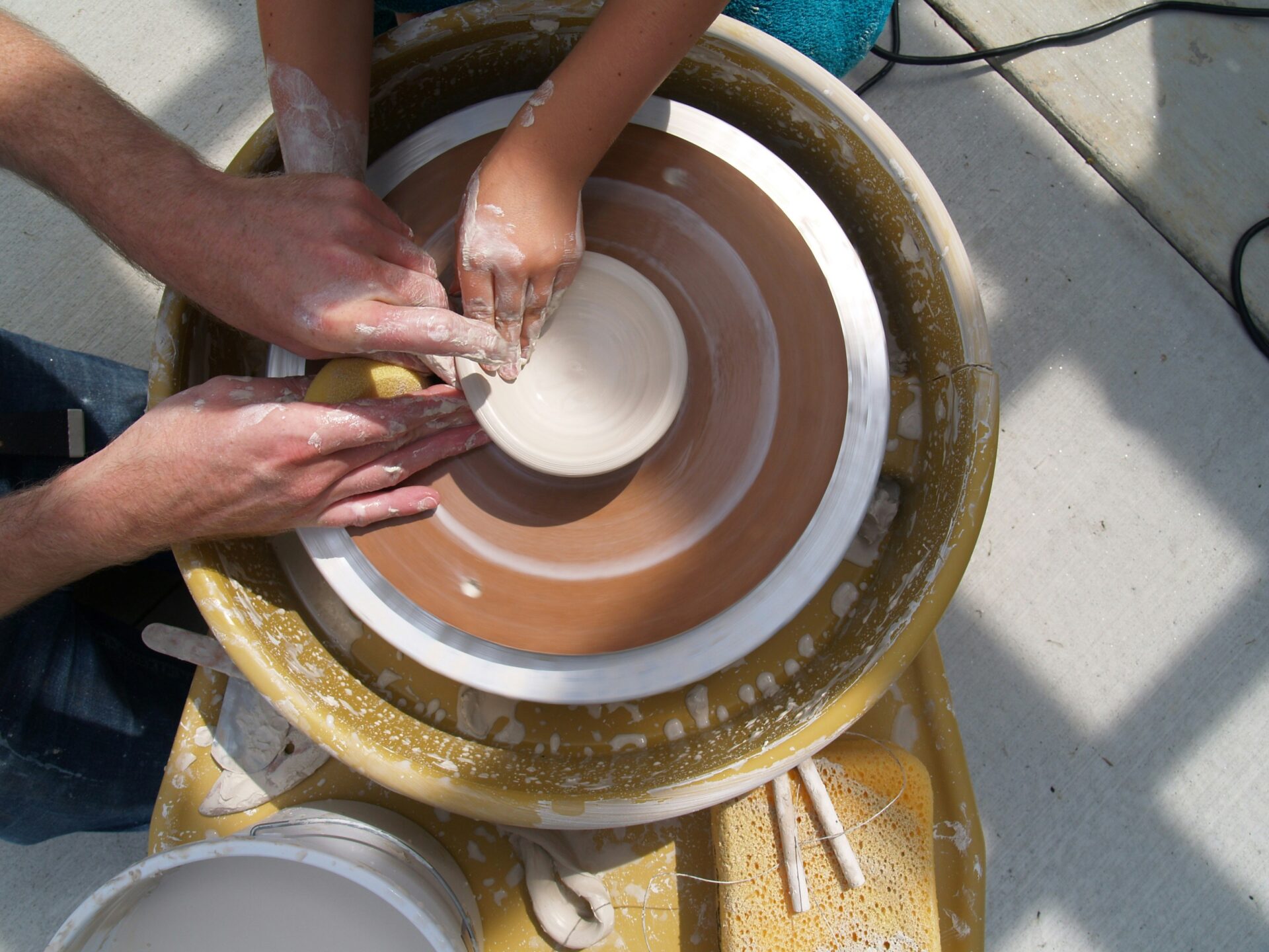 Adult helping a child doing pottery