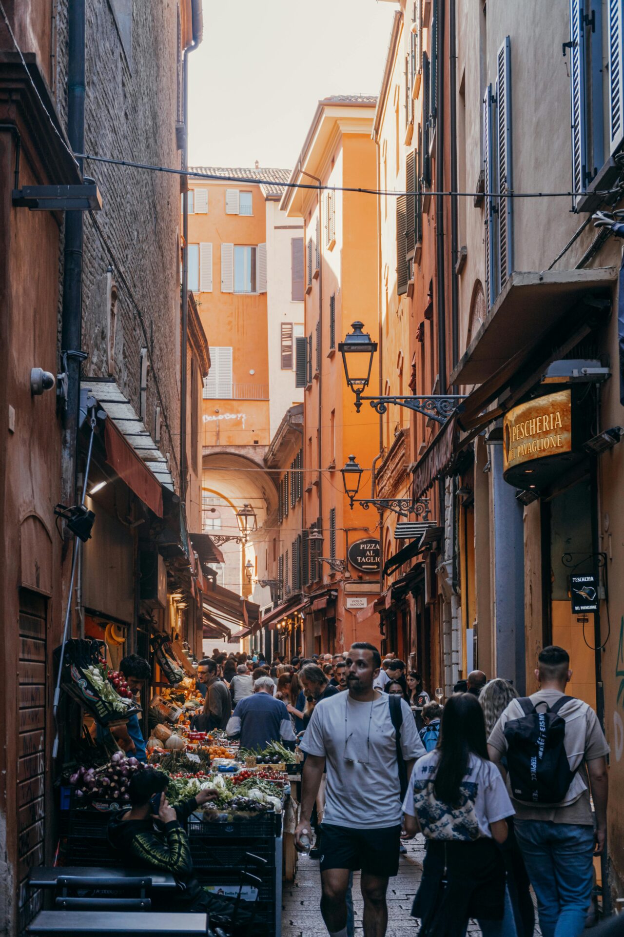 A lively street market in Bologna, Italy, bustling with people exploring fresh produce, local delicacies, and traditional Italian goods.