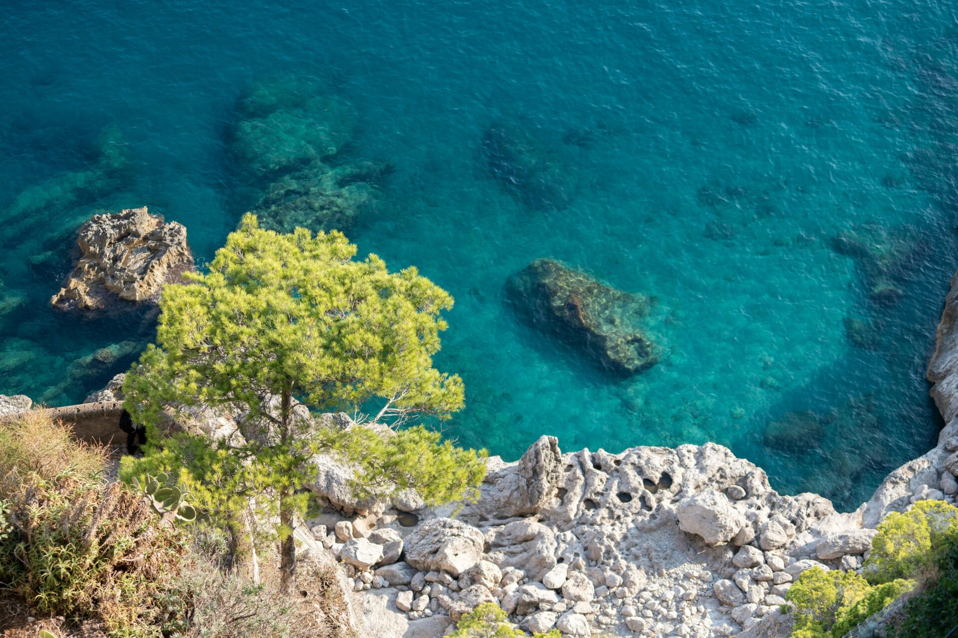 A scenic view of Capri Island, with dramatic cliffs rising from the turquoise Mediterranean Sea