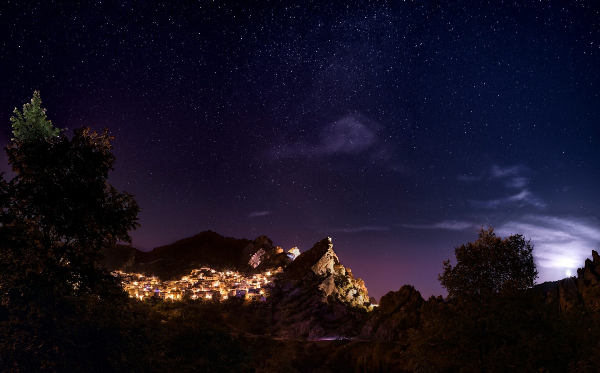 Castelmezzano glows under golden nighttime lighting, nestled against the rugged peaks of the Lucanian Dolomites.