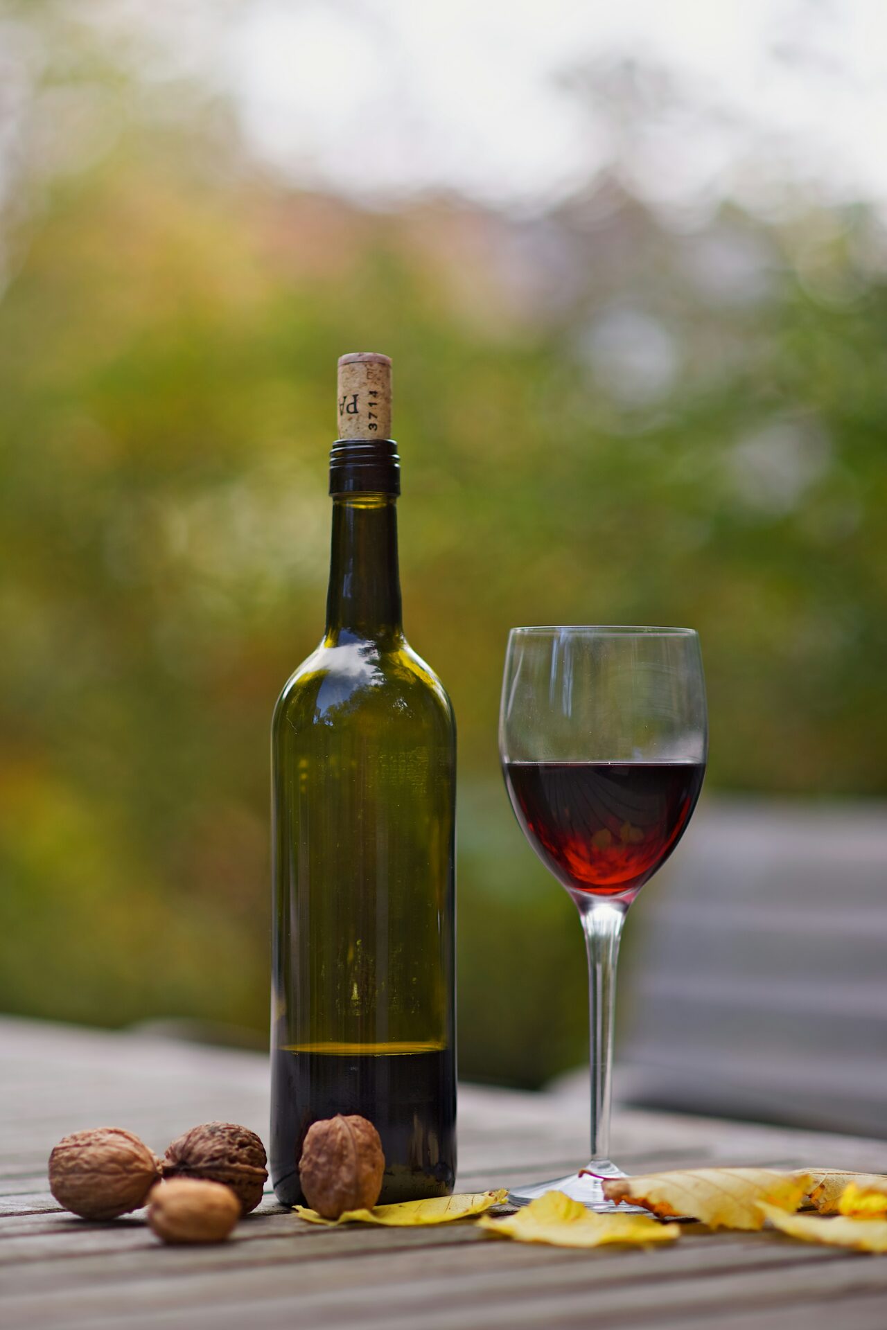 A glass of red wine set on a rustic wooden table overlooking the rolling vineyards of Chianti, Italy