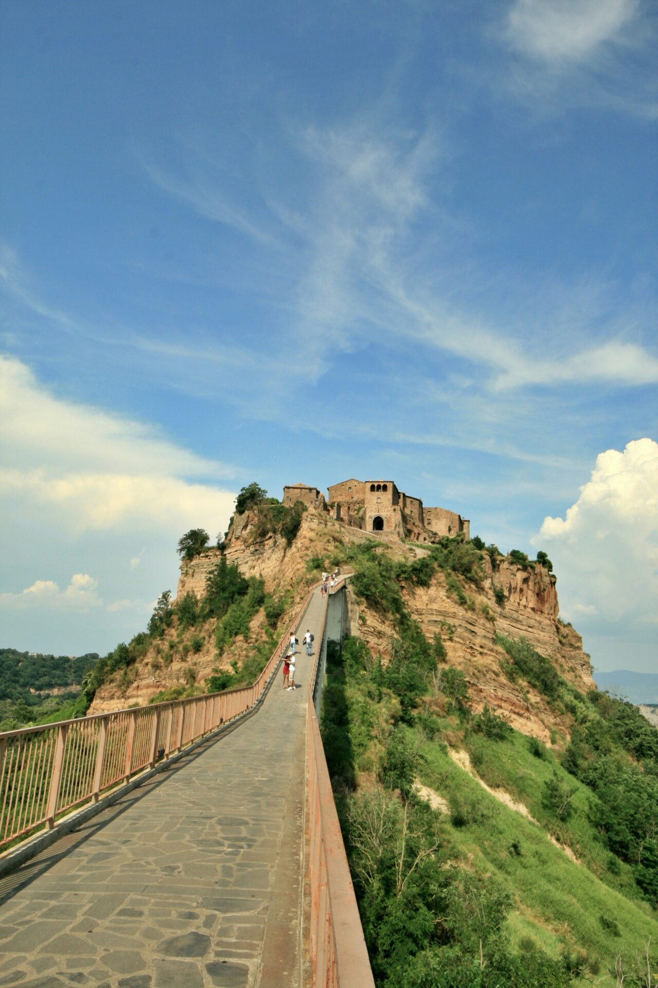 Civita di Bagnoregio, Italy – a stunning hilltop village perched atop a narrow plateau, connected by a long pedestrian bridge and surrounded by dramatic valleys and cliffs.