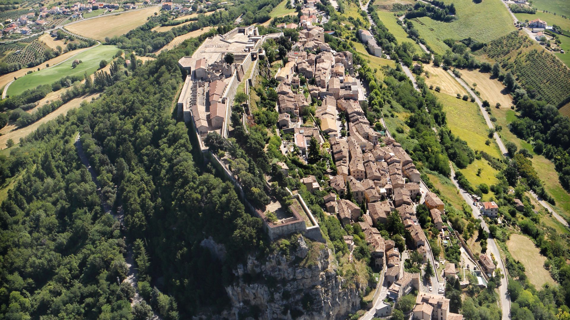 Image shows the aerial view of Civitella del Tronto perched on a rocky cliff in Italy's Abruzzo region.