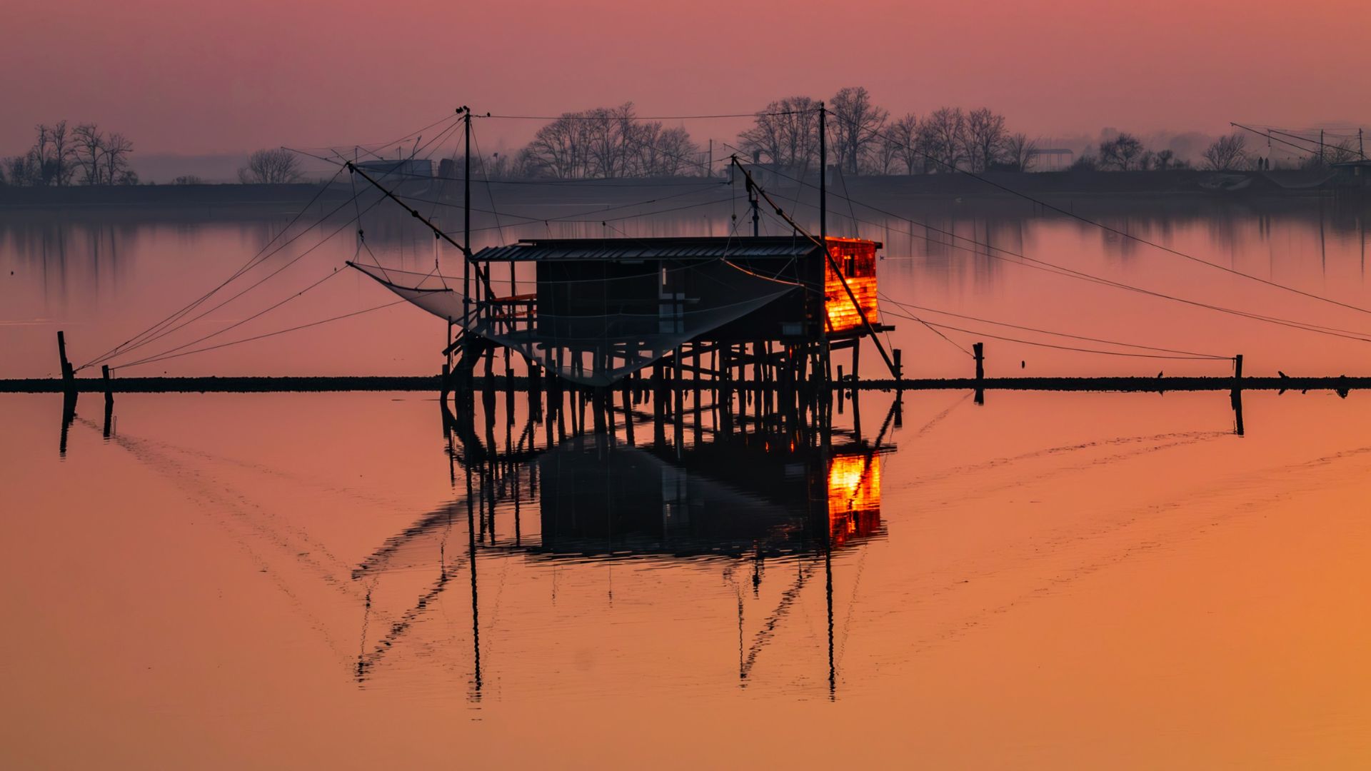 The image depicts a fishing hut in a lagoon in Comacchio.