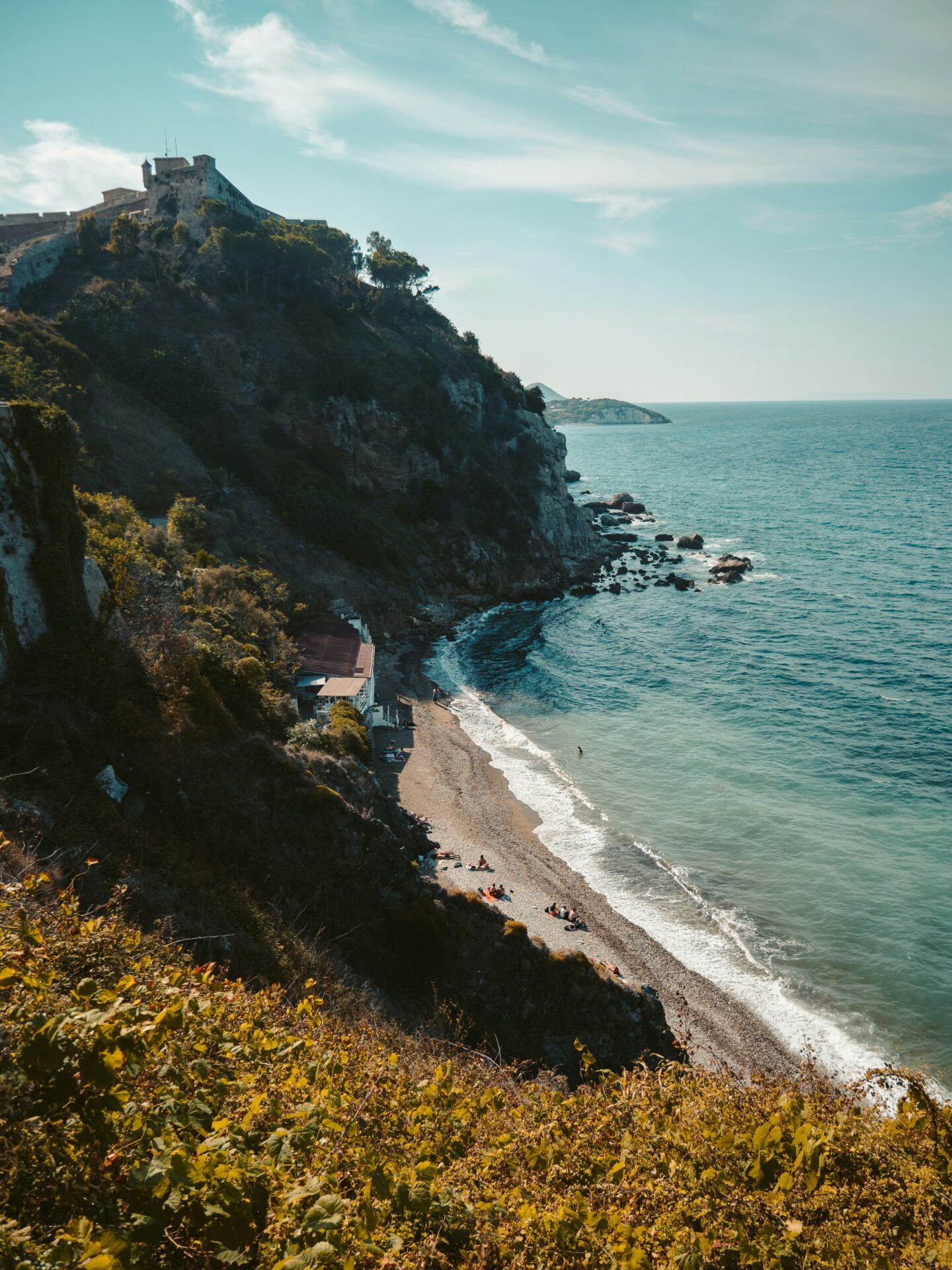 Stunning coastal view of Elba Island, part of the Tuscan Archipelago, with clear blue waters, rugged cliffs, and lush greenery under a bright Mediterranean sky.