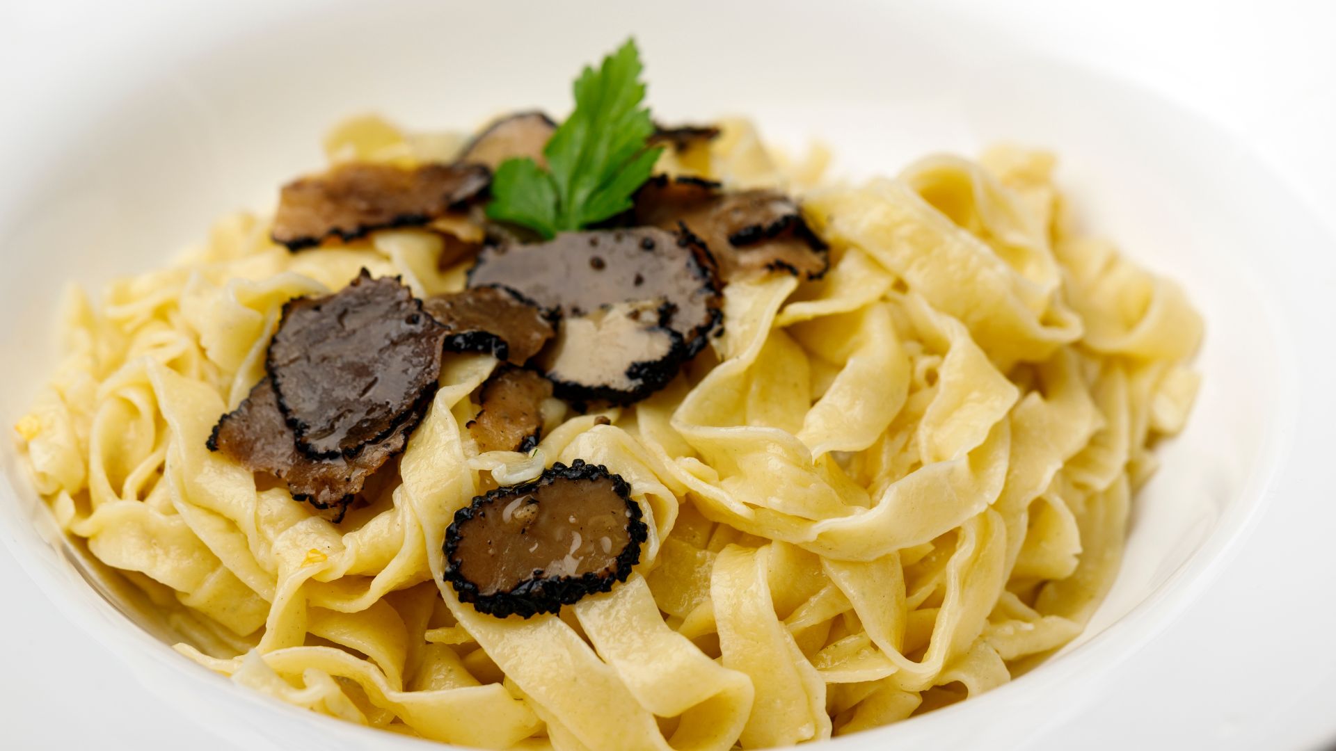 Image shows pasta with black truffle