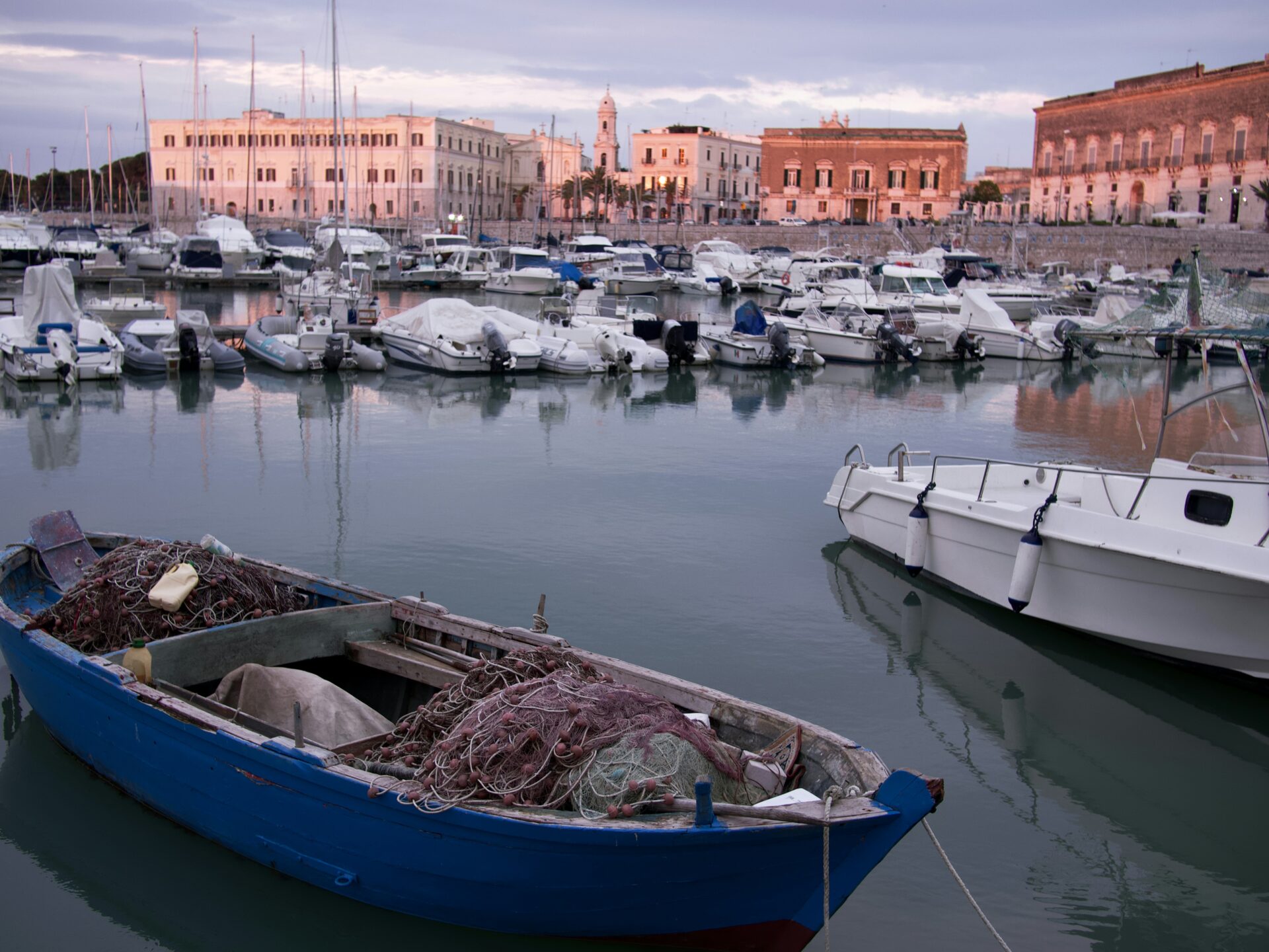 Colorful fishing boats moored in the tranquil harbor of Trani, Italy