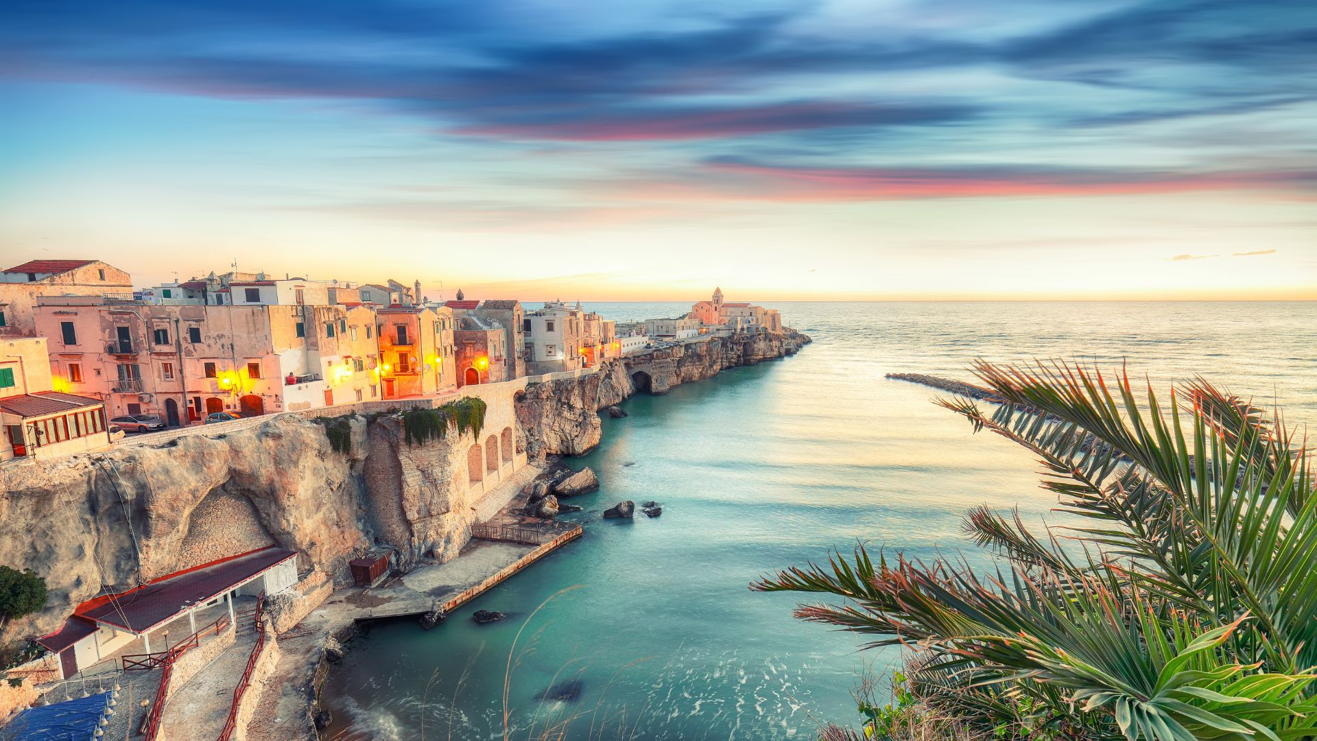 The image shows a coastal landscape featuring a natural arch formation, known as an arch or sea arch, in the Gargano National Park, located in the Apulia region of southeastern Italy.