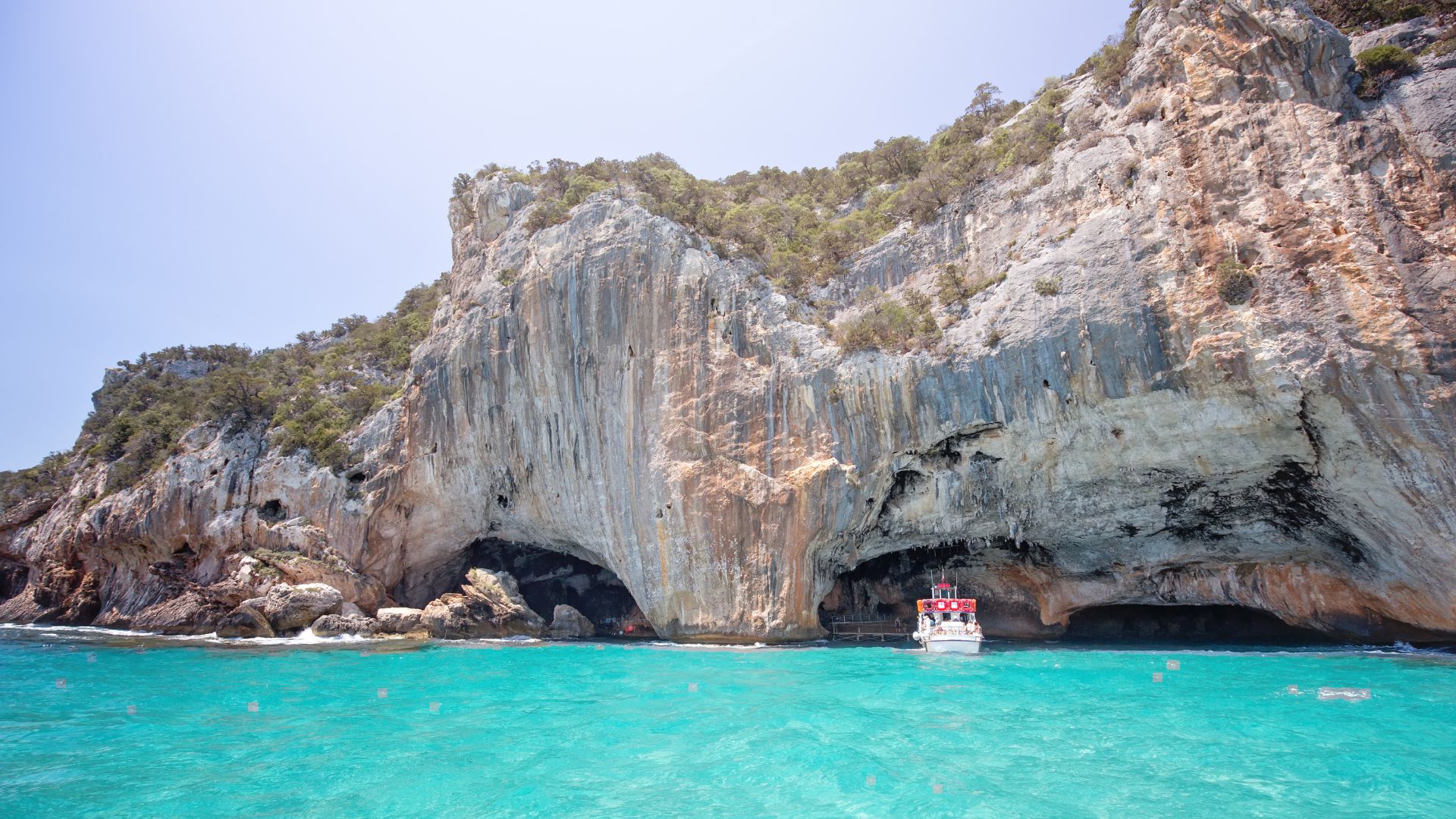 The image shows Grotta del Bue Marino, Tremiti Islands, Italy characterized by clear turquoise waters, rocky cliffs, and a cove.