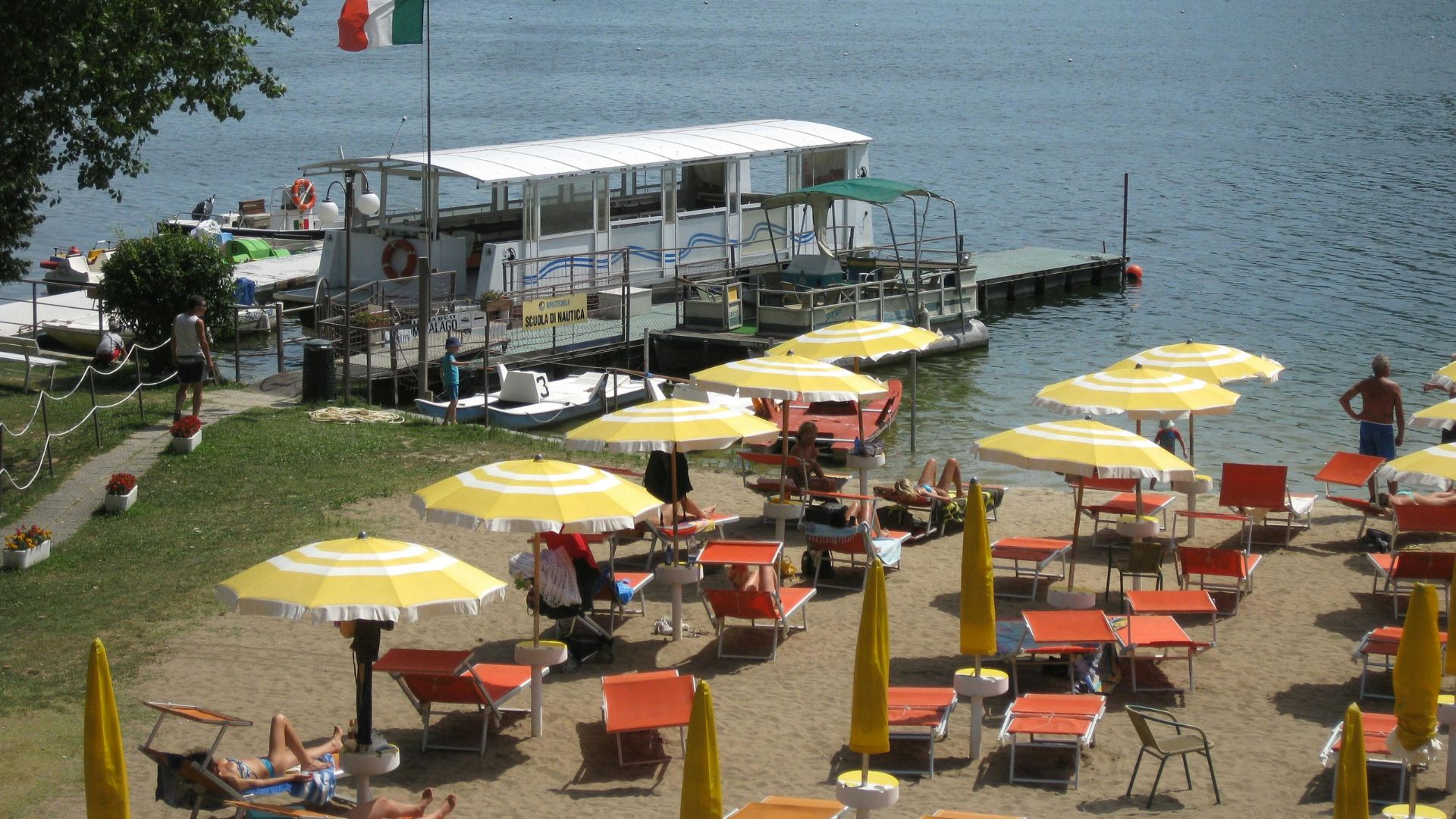 Beach scene with yellow umbrellas and lounge chairs, with a boat on the water in the background.