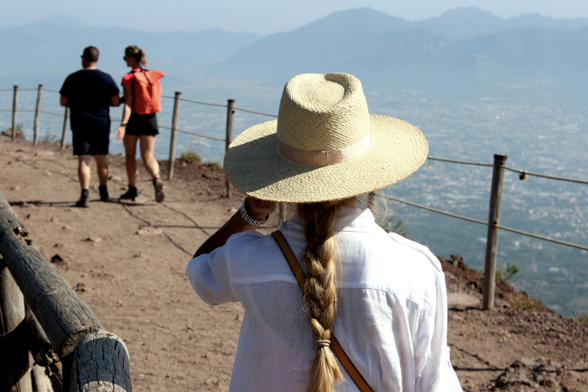 Tourists hiking along the crater rim of Mount Vesuvius under a clear blue sky