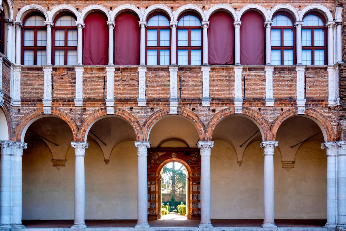 The image shows the Palazzo Costabili, also known as the National Archaeological Museum of Ferrara, located in Ferrara, Italy. It is a notable example of Renaissance architecture, characterized by its grand design and the use of brick and stone in its construction. The palazzo features a distinctive facade with arched openings, columns, and decorative elements. It is recognized as an important cultural and historical landmark in Ferrara. 