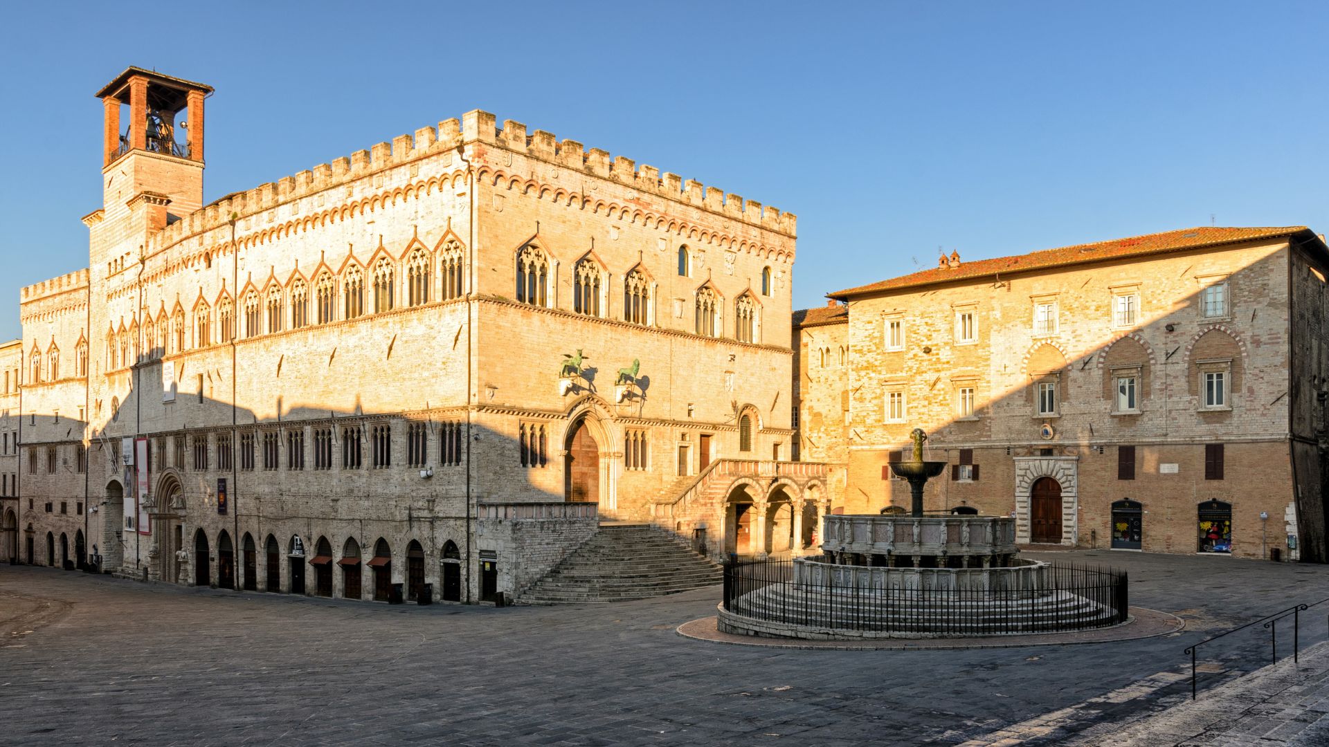 The image shows the Palazzo dei Priori in Perugia, Umbria, Italy, specifically featuring its facade and the Fontana Maggiore in Piazza IV Novembre.