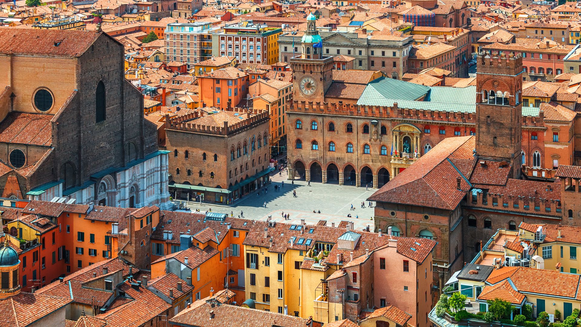 Aerial view of Piazza Maggiore in Bologna, Italy, showcasing the historic square and surrounding buildings with red-tiled roofs.