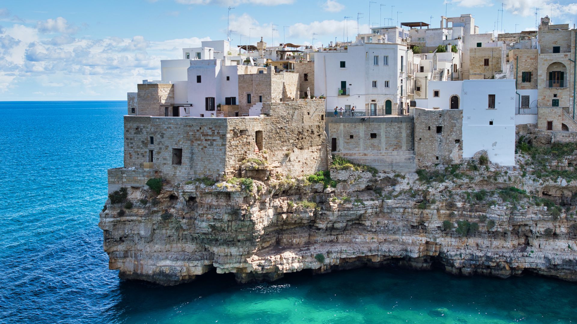 Image shows the clear turquoise water and cliff of Polignano a Mare, Italy 
