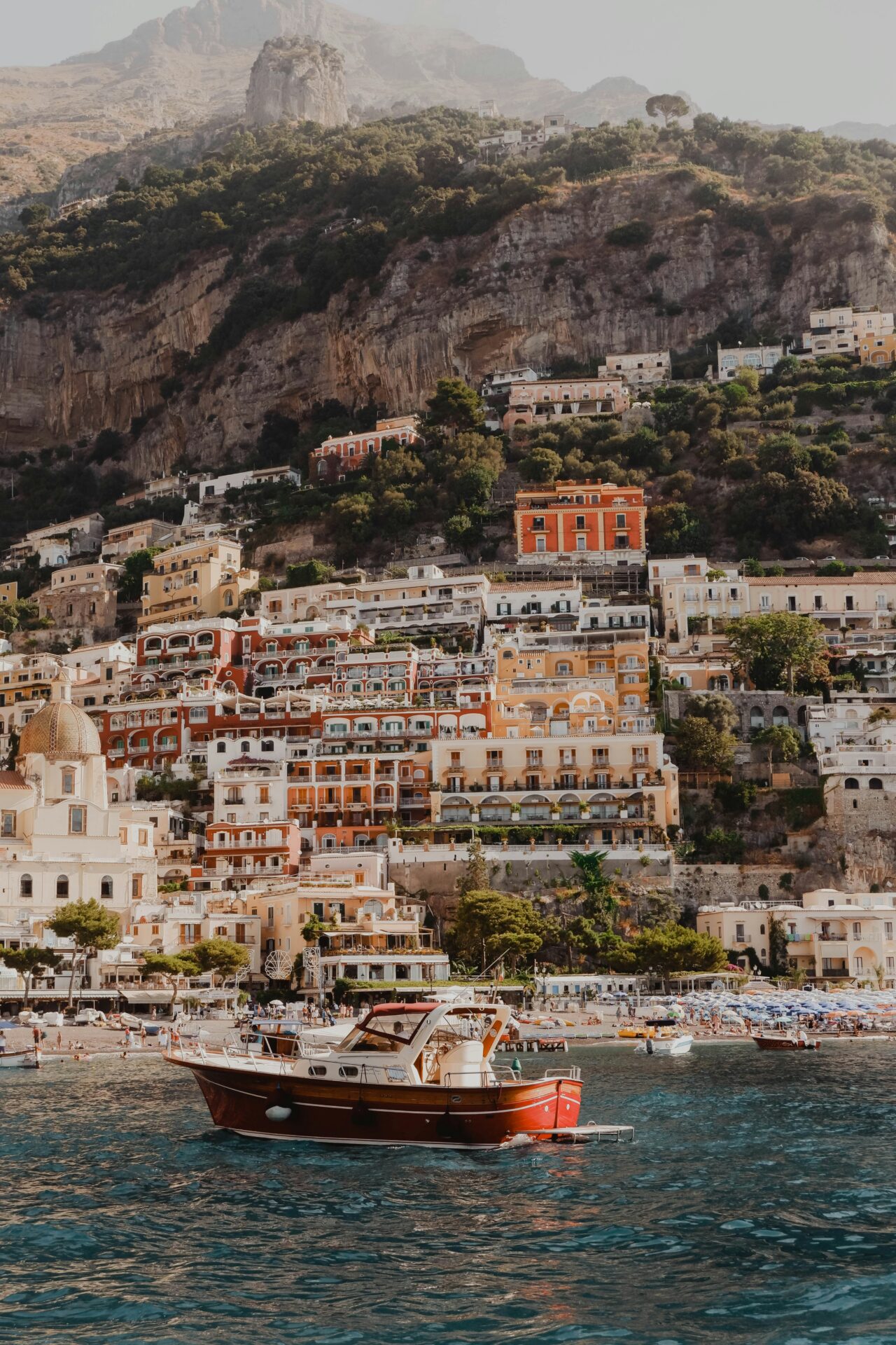 Colorful hillside buildings of Positano with a ferry approaching across the blue sea.
