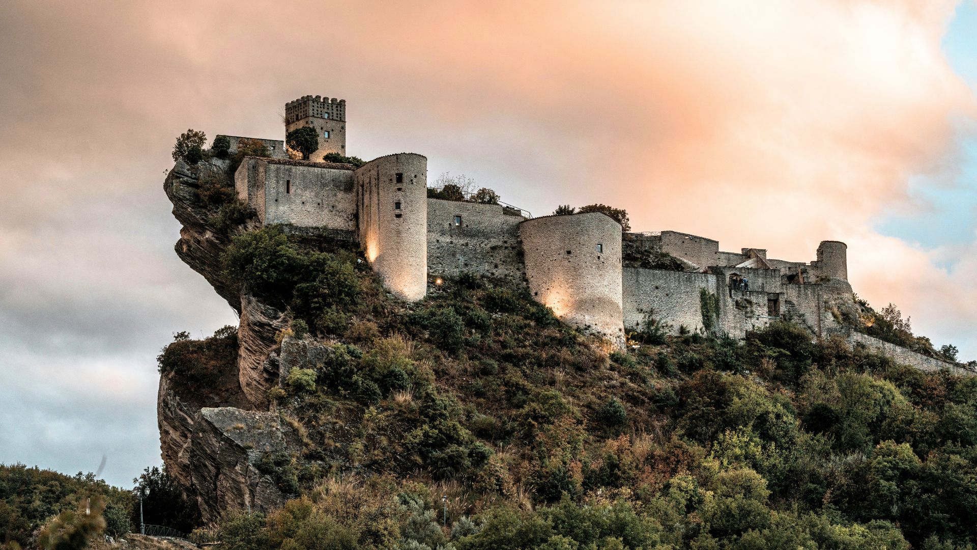 Image shows Roccascalegna Castle clinging dramatically to a sheer basalt cliff.