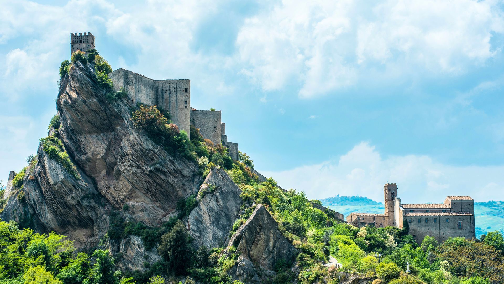 Image shows Roccascalegna Castle clinging dramatically to a sheer basalt cliff.