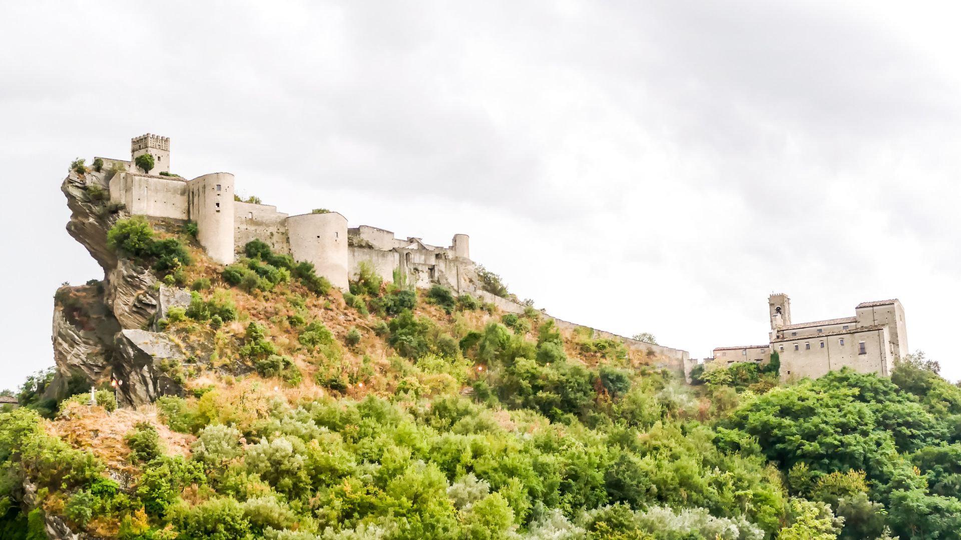 Image shows Roccascalegna Castle clinging dramatically to a sheer basalt cliff.