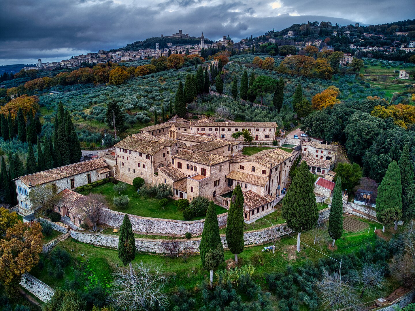 San Damiano complex in Assisi, a serene cluster of historic stone buildings and courtyards nestled among olive groves, with views of the Umbrian valley