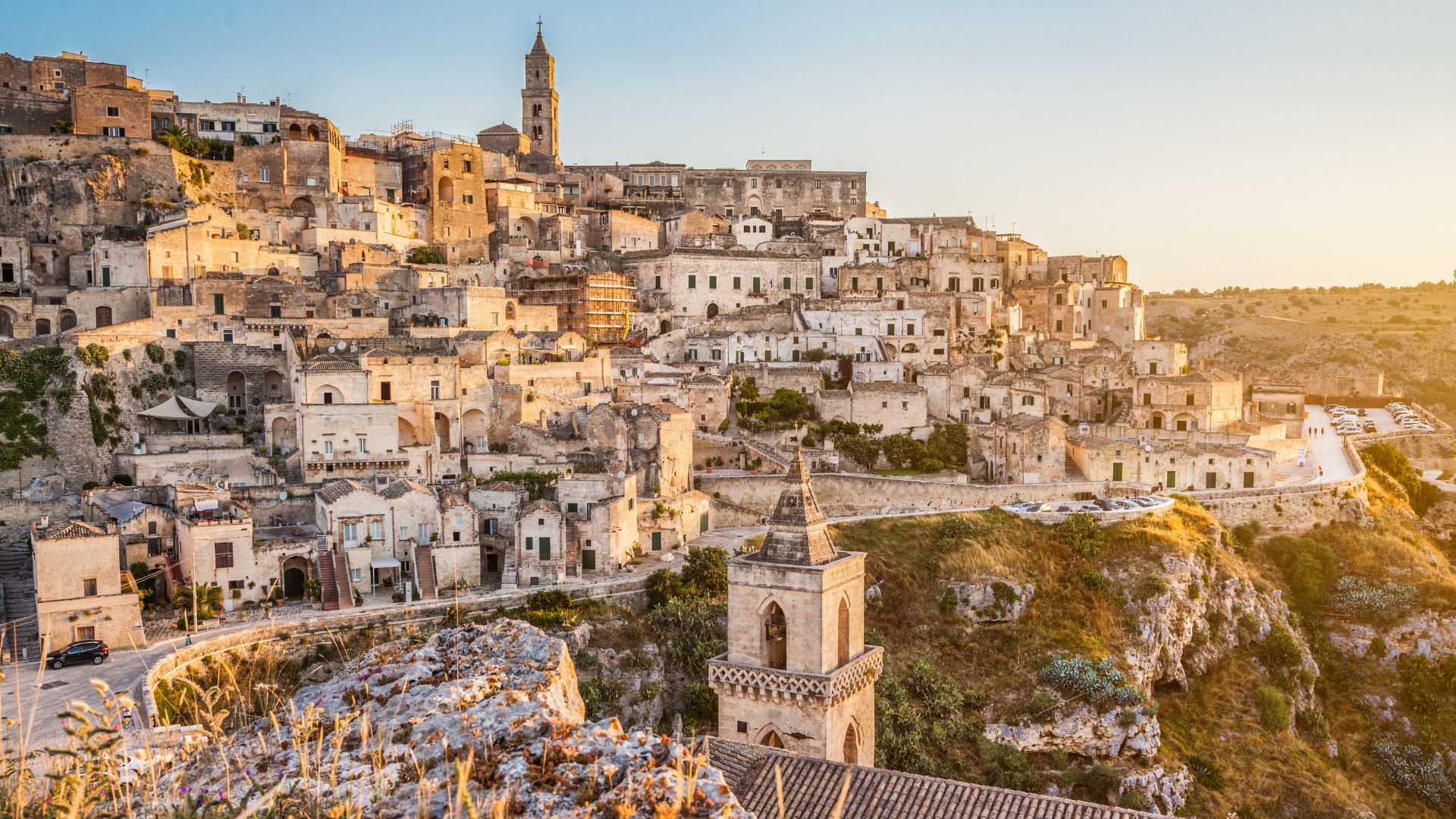 Sassi di Matera, Italy, featuring ancient cave dwellings and buildings, illuminated by warm sunlight. The image captures the unique architecture and landscape of this historic city. 