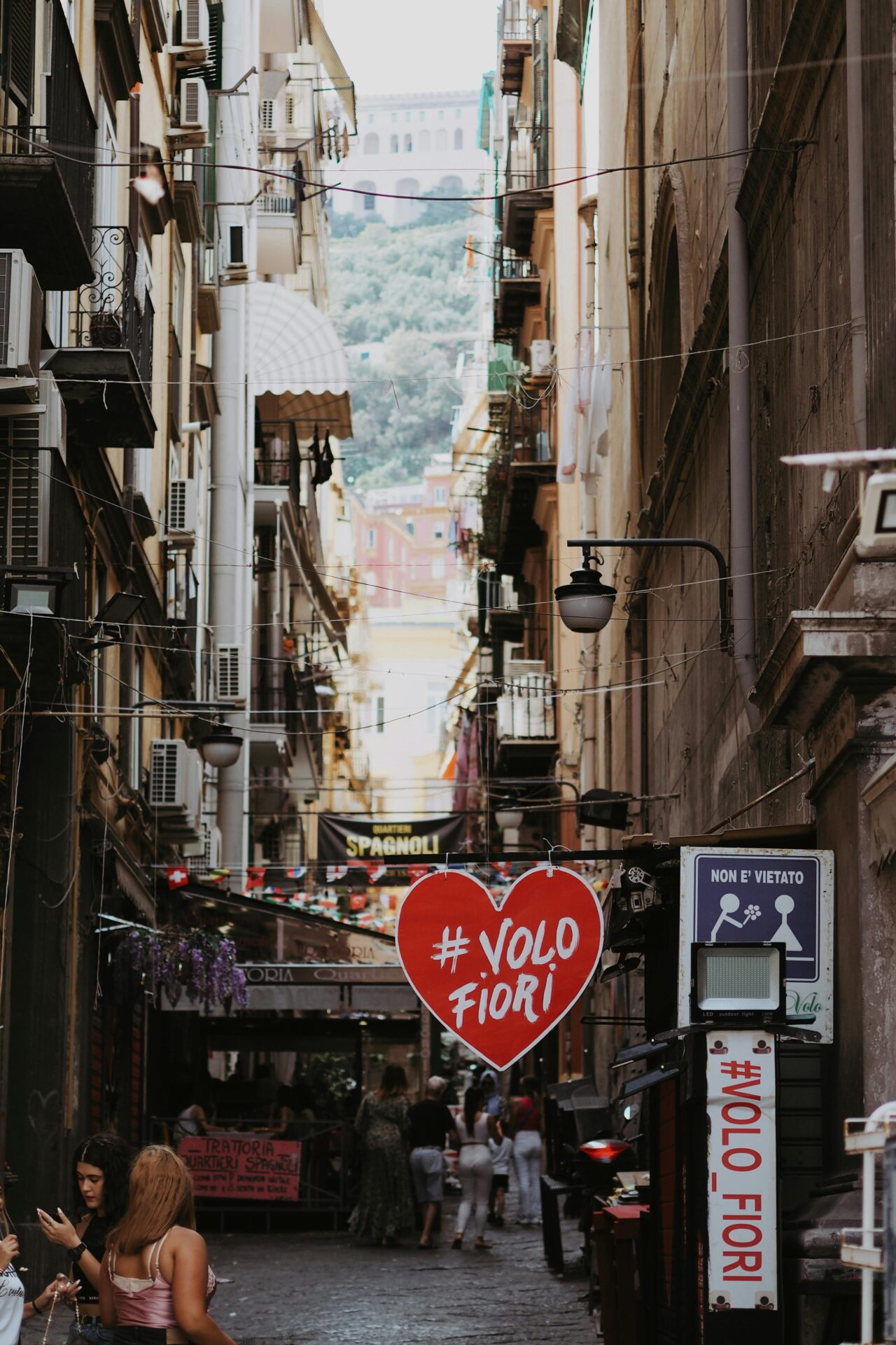Bustling scene along Spaccanapoli with locals, tourists, and colorful buildings.