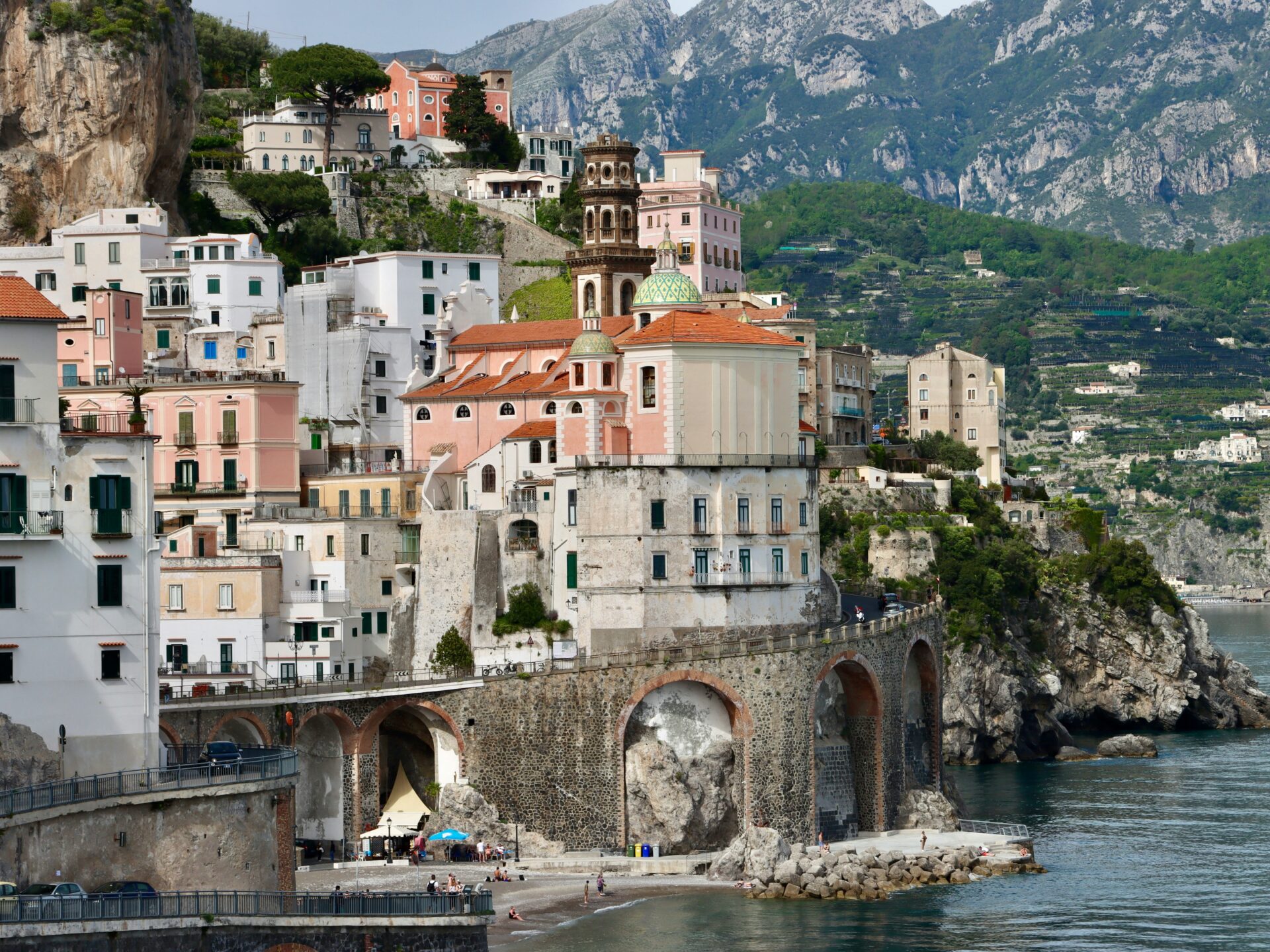 Seaside view of Spiaggia di Atrani with colorful buildings and arched bridges in Atrani, Italy.