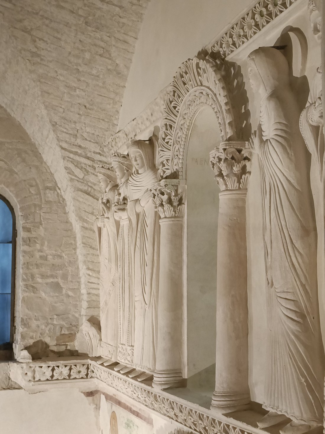 Intricate stone carvings of female figures and decorative arches inside the Tempietto Longobardo in Cividale del Friuli, Italy.