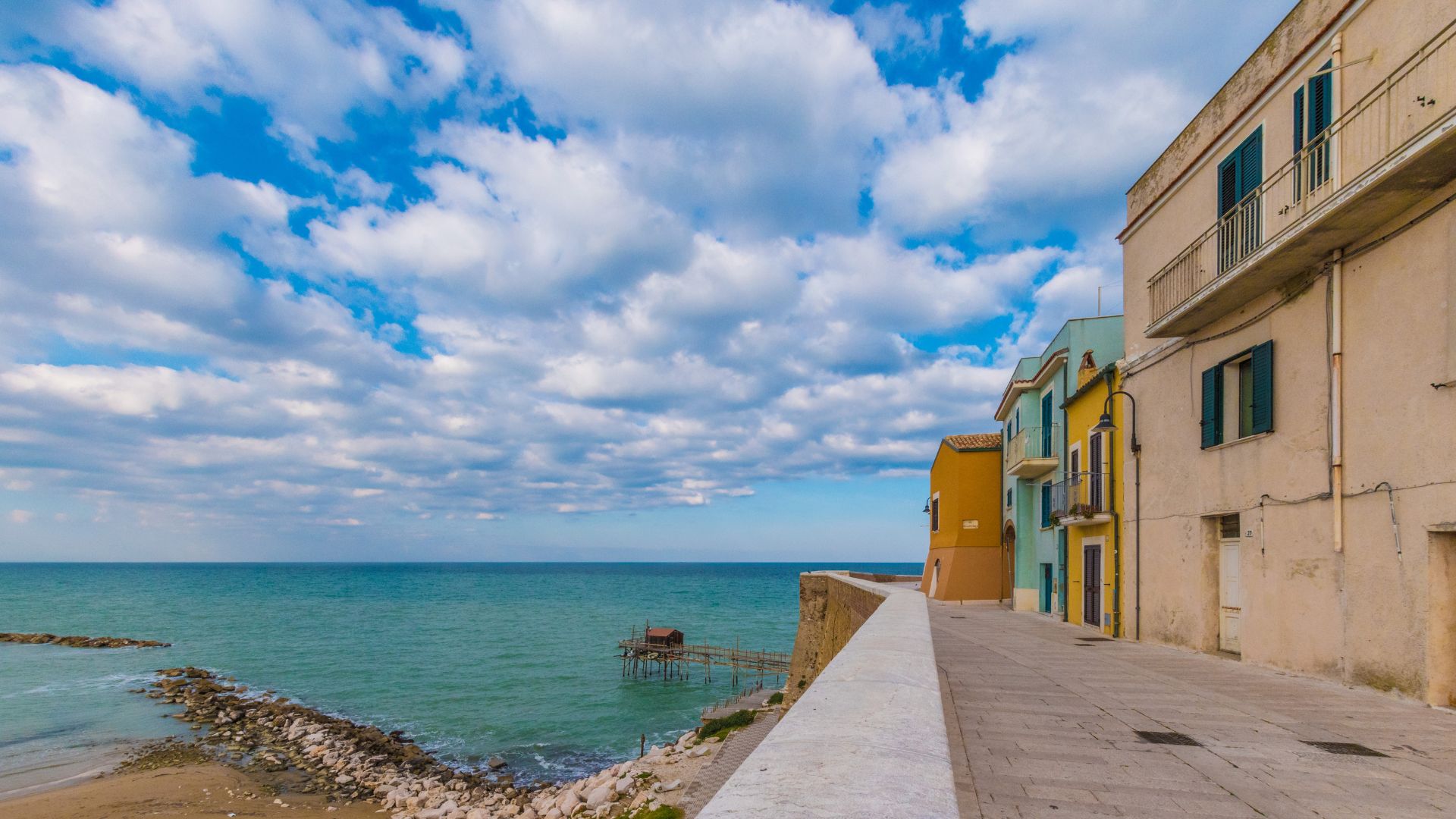 The image shows Termoli, Molise, Italy, specifically the old town section, known as Borgo Vecchio, characterized by its colorful houses and narrow streets