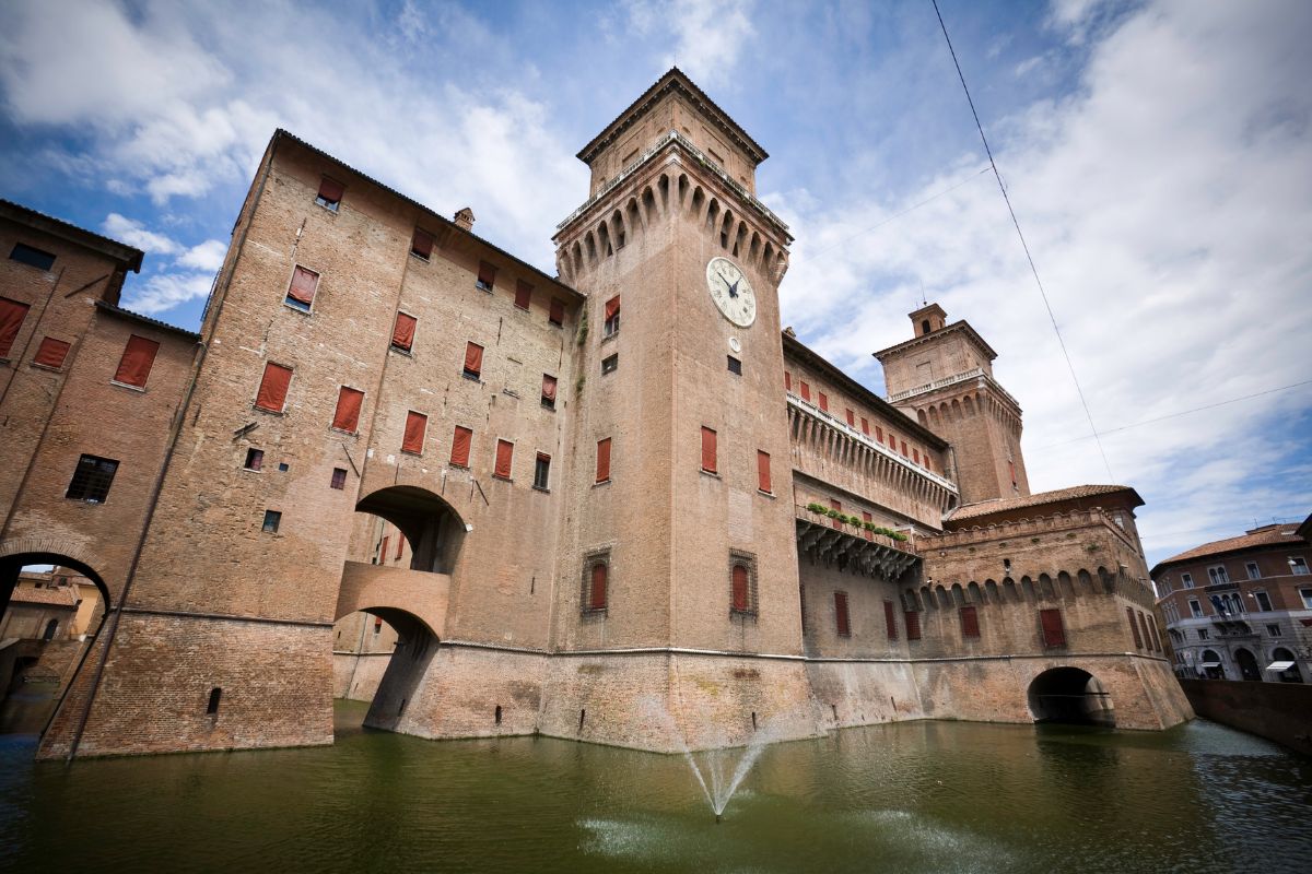 Image of The Castello Estense showing its  red brick towers and moat