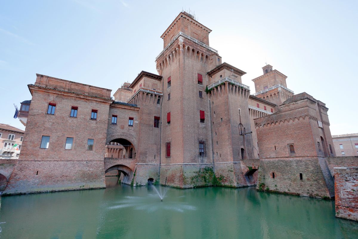 Image of The Castello Estense showing its  red brick towers and moat