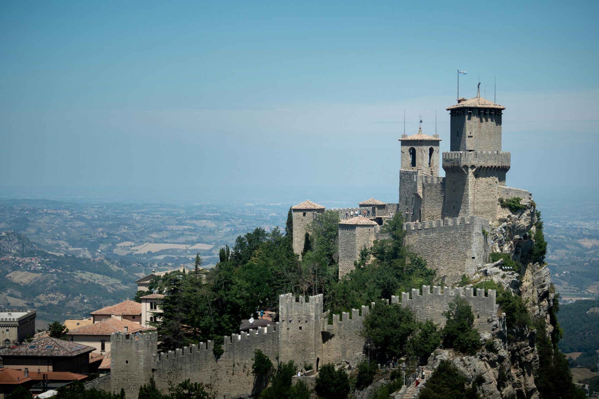 Scenic view of a medieval castle in Udine, Italy, perched on a hilltop with stone towers, fortified walls, and a sweeping view of the countryside below.