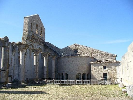 Historic ruins at Venosa, including Roman and early Christian structures, spread across a grassy excavation area in southern Italy.