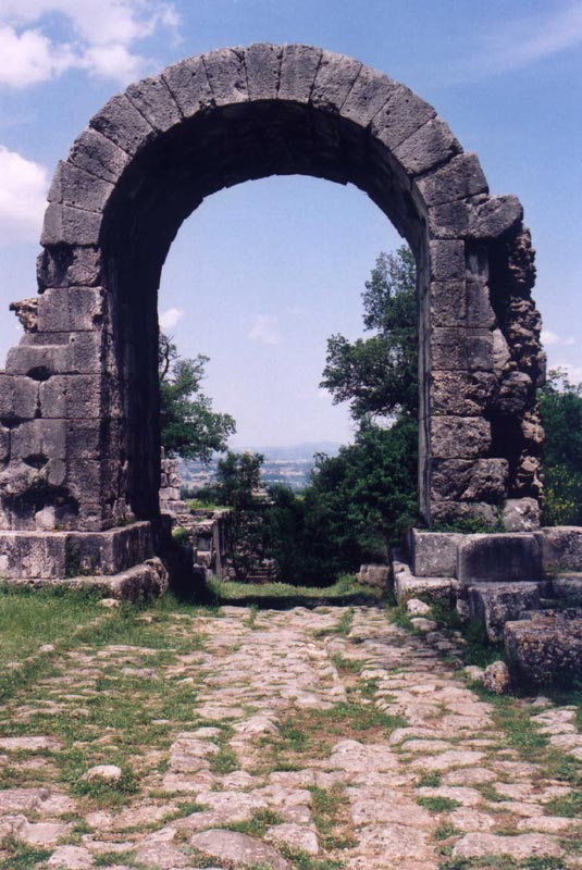 Ancient Roman road Via Flaminia passing through Spoleto, Umbria, with stone ruins and scenic views.