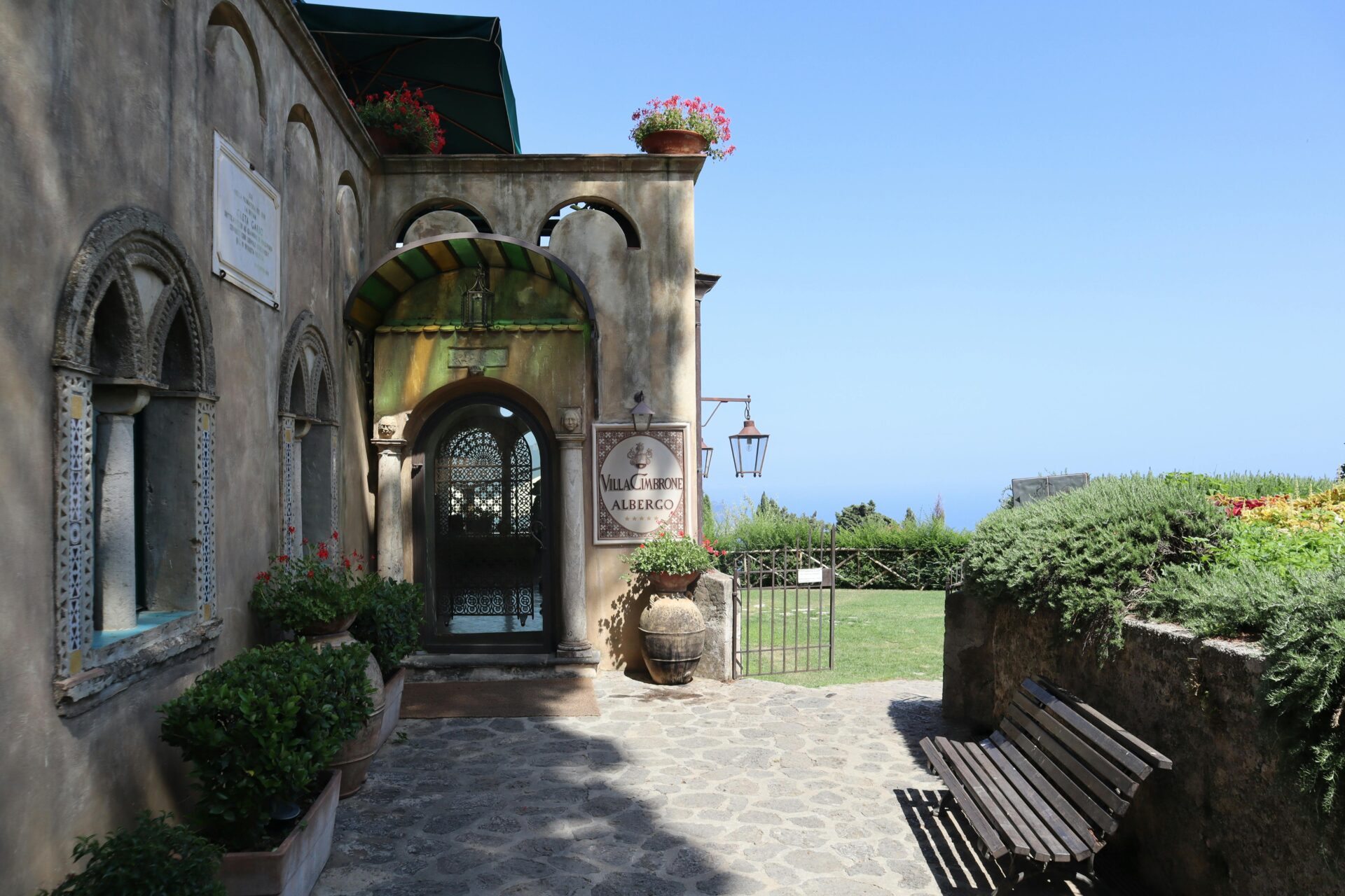 Entrance to Villa Cimbrone with a rustic stone path, arched doorway, and views of the garden and sea in Ravello, Italy.