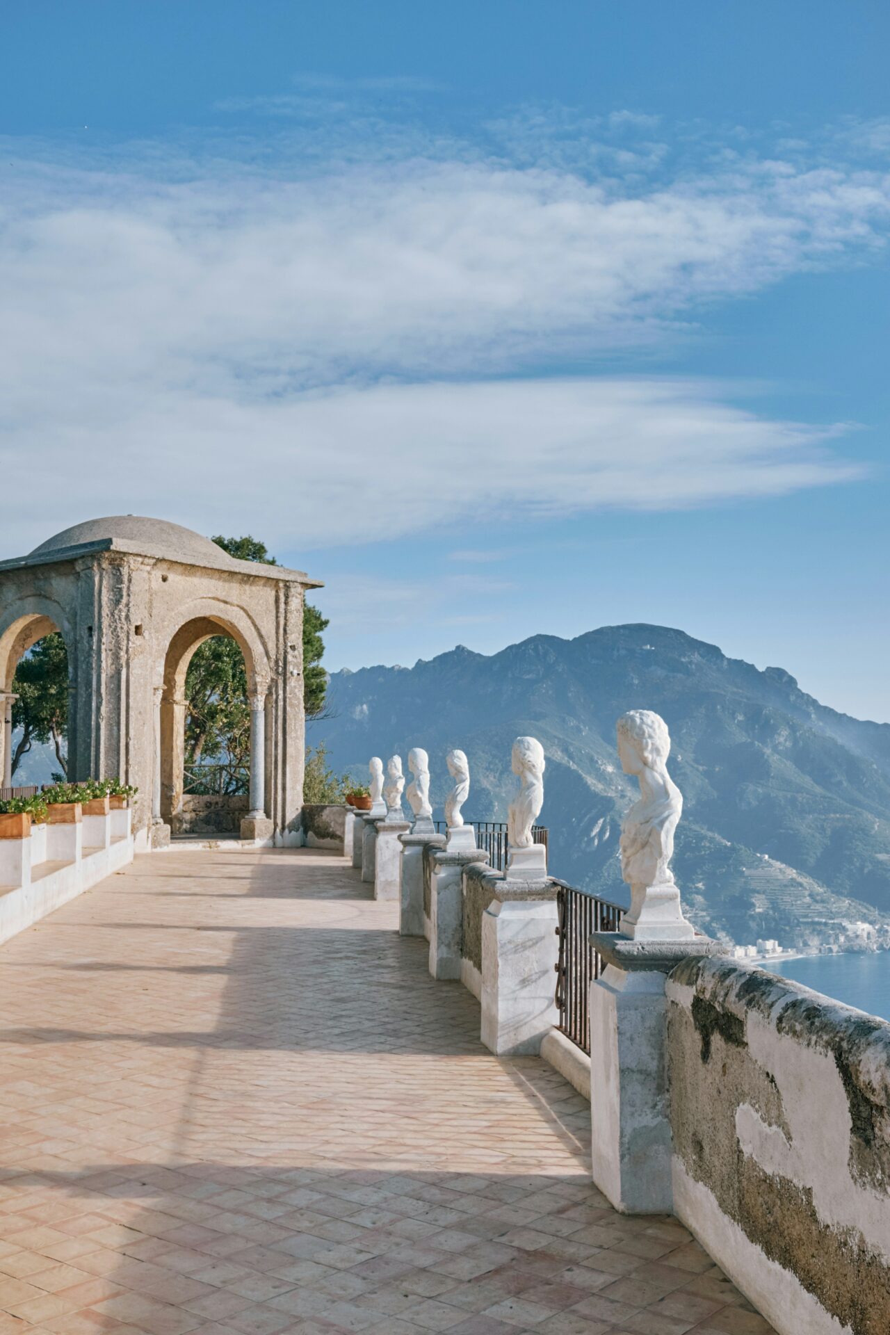 Terrace of Villa Cimbrone in Ravello, Italy, with marble statues overlooking the mountains and the sea.