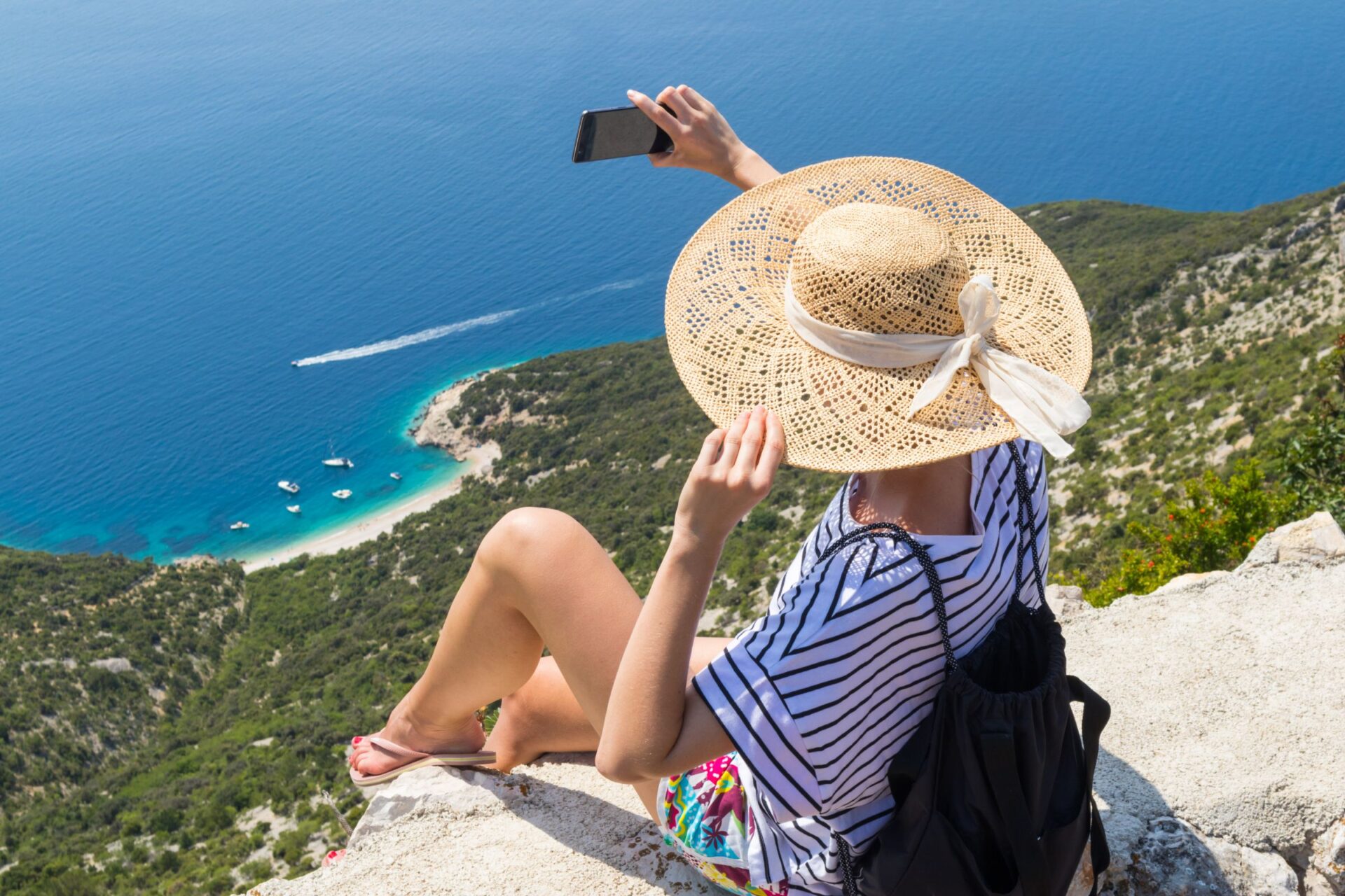 a woman doing selfie on top a hill overlooking the beach