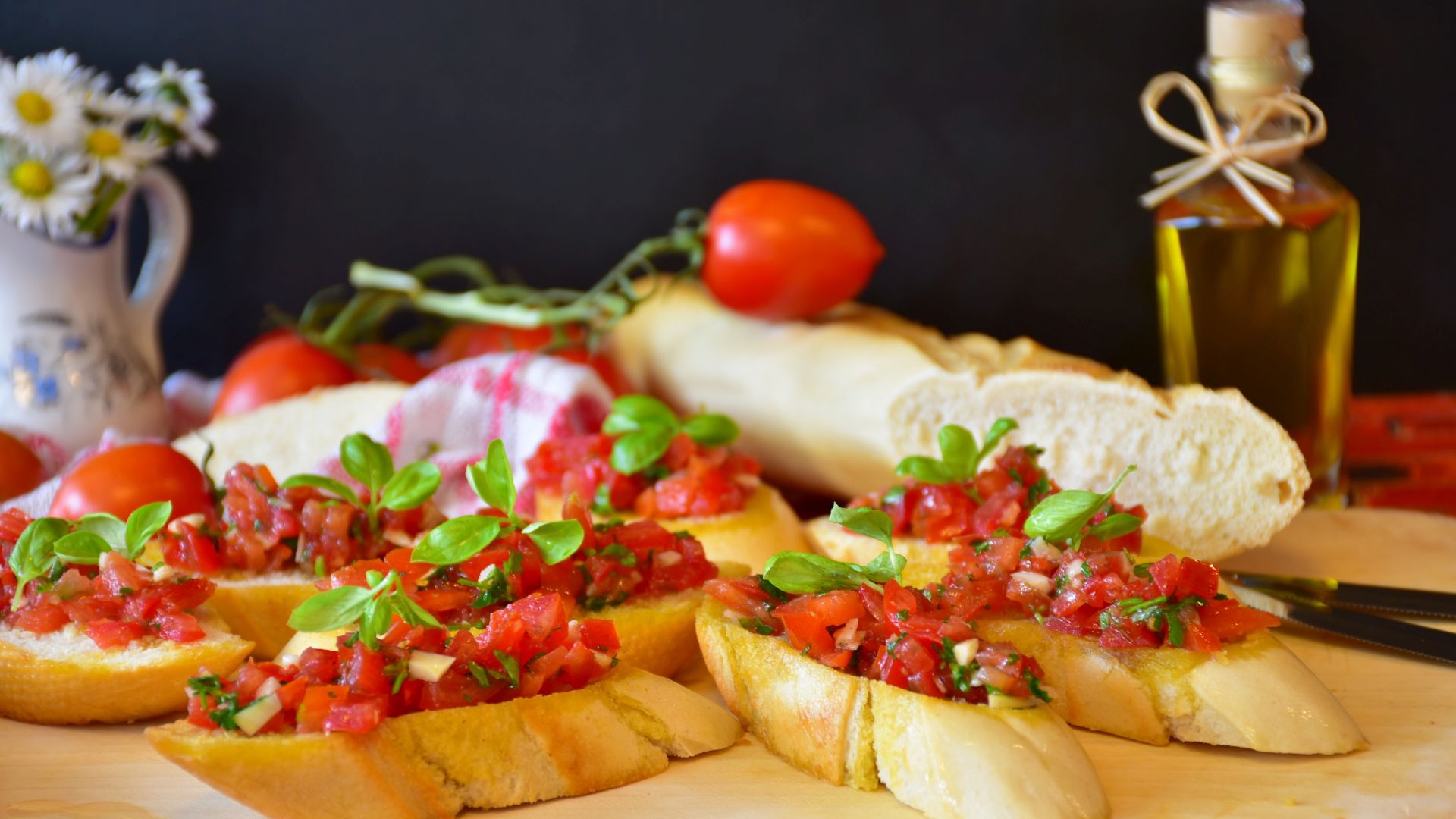 Image shows bruschetta topped with peppery olive oil