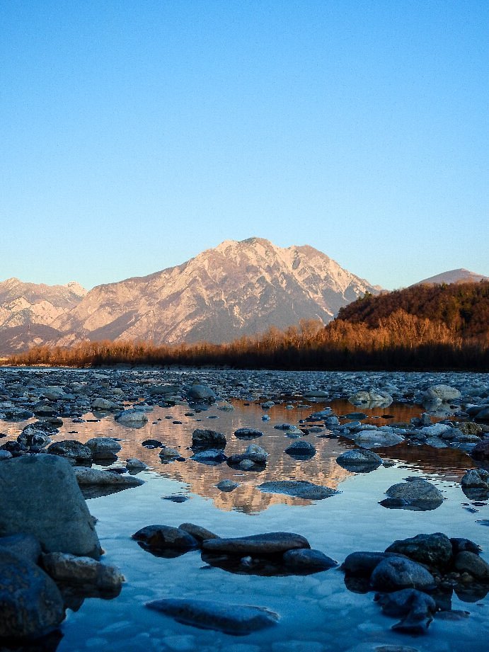 Crystal-clear waters of the Tagliamento River flowing over smooth rocks