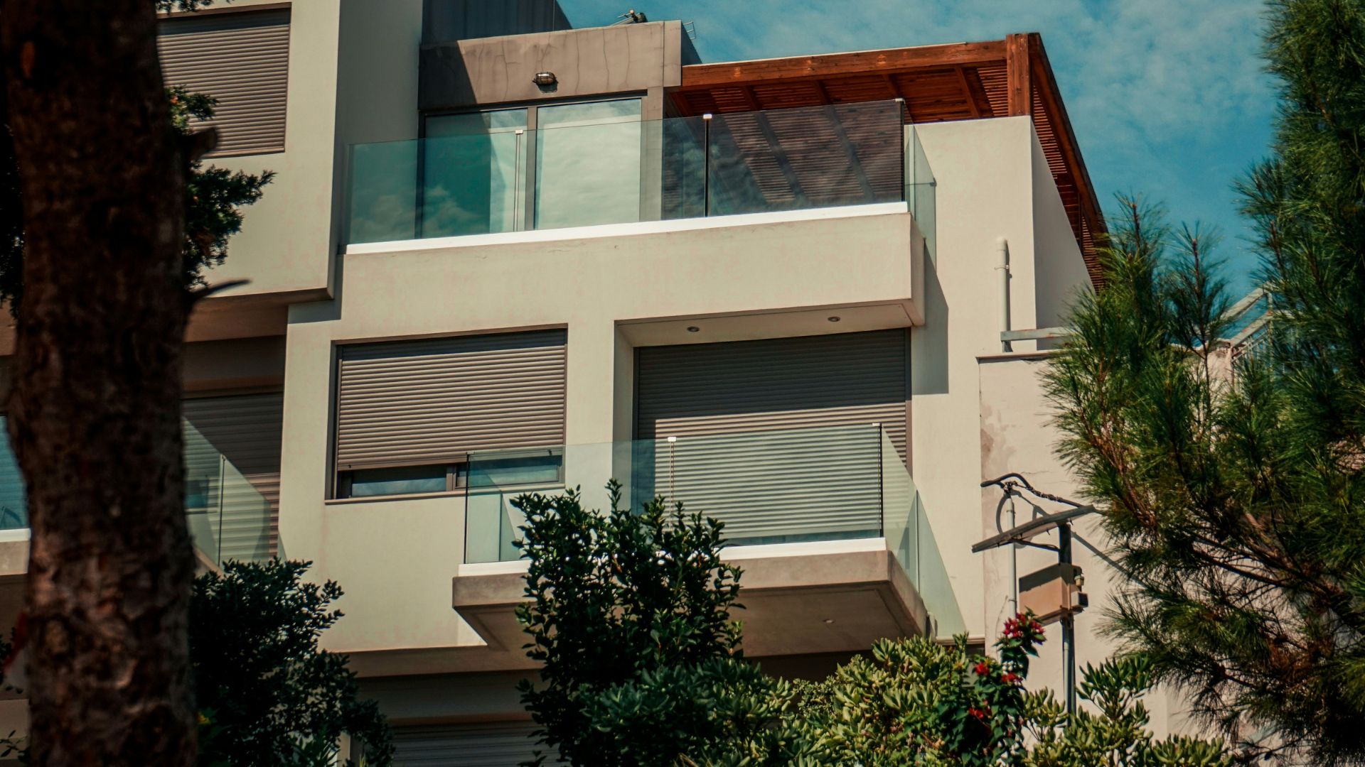 Exterior view of a modern villa in Crete, surrounded by lush greenery and a blue sky.