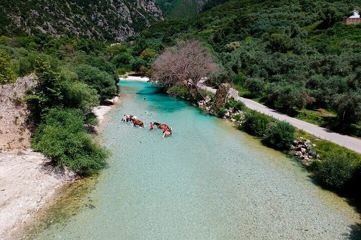 Tourists wading through the cool, shallow waters of the Acheron River