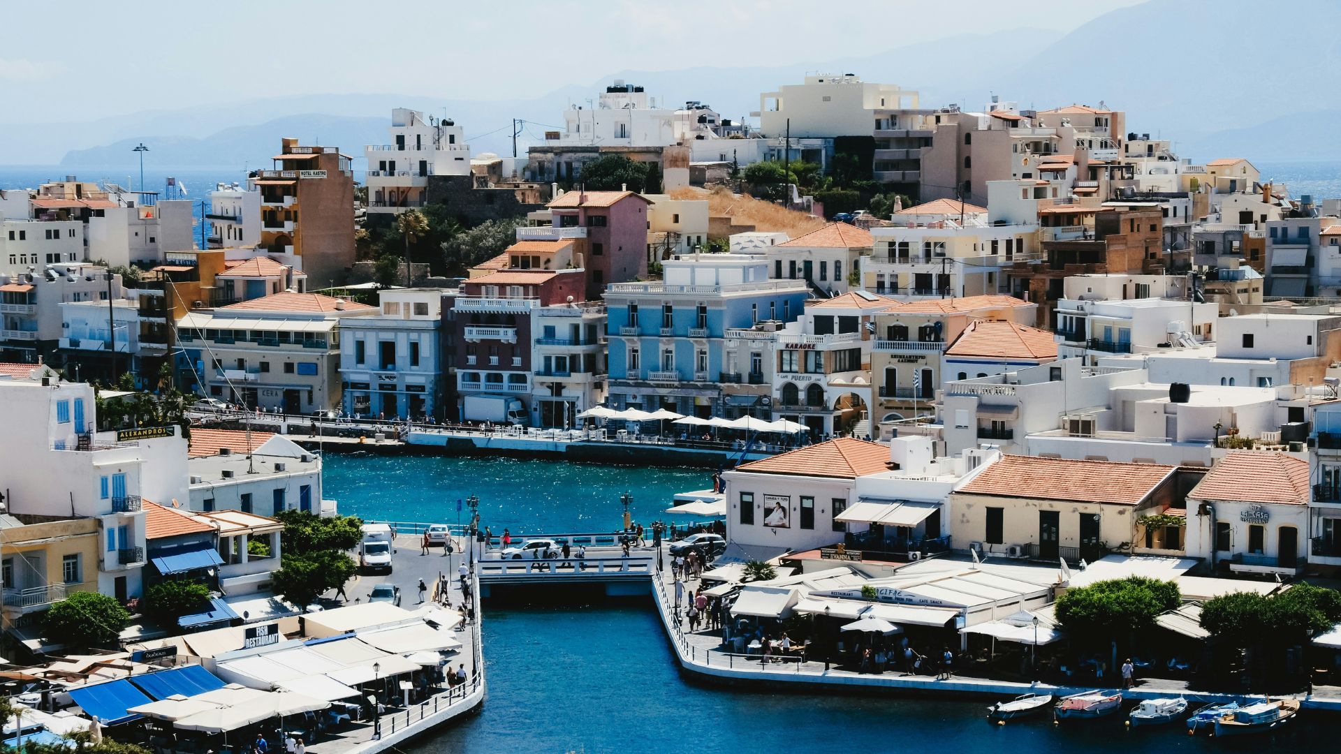 A scenic view of Agios Nikolaos, Crete, featuring Lake Voulismeni surrounded by buildings.
